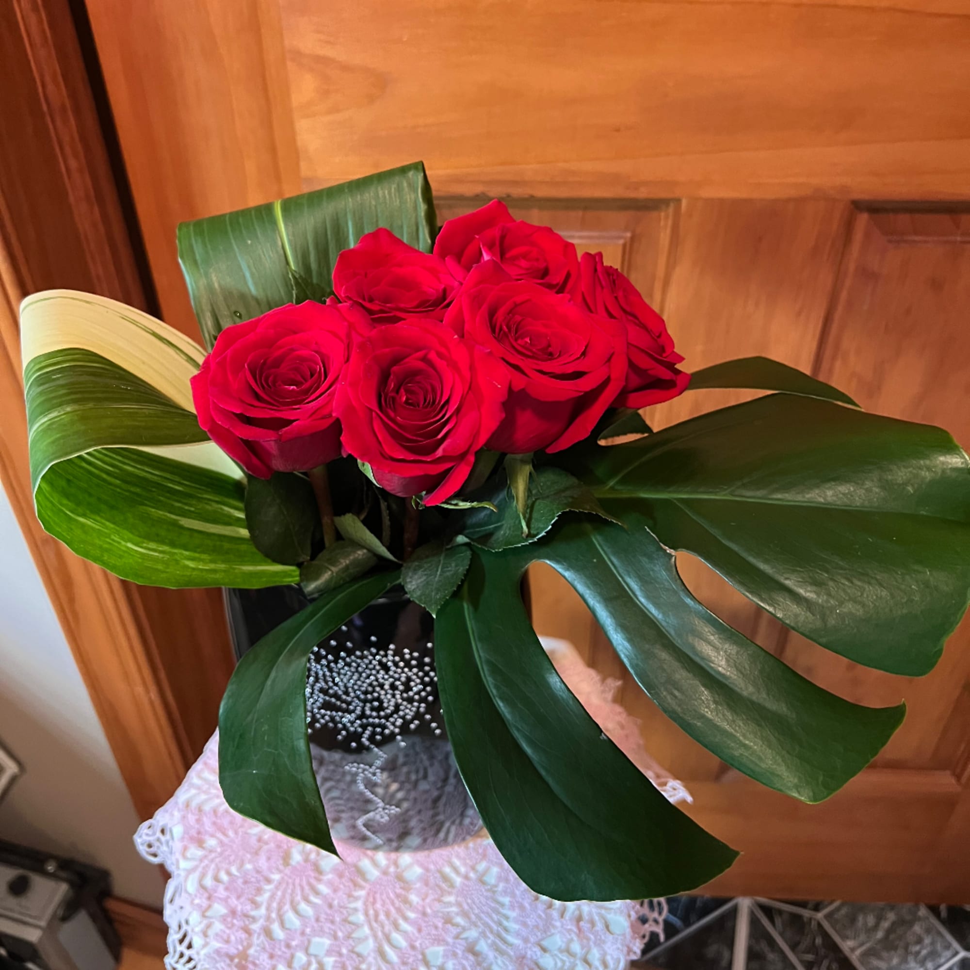 Red roses arranged in a black vase with large green leaves