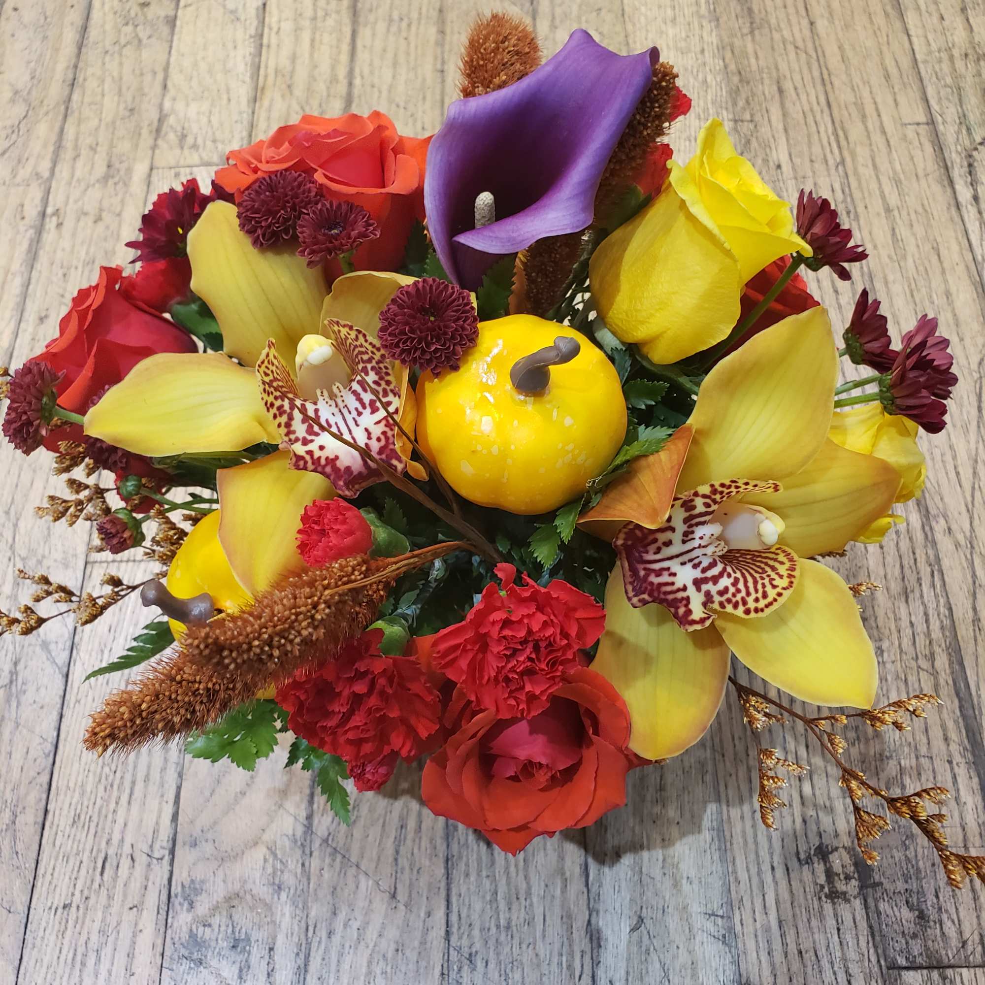 Colorful bouquet with roses, calla lilies, and orchids on a wood floor