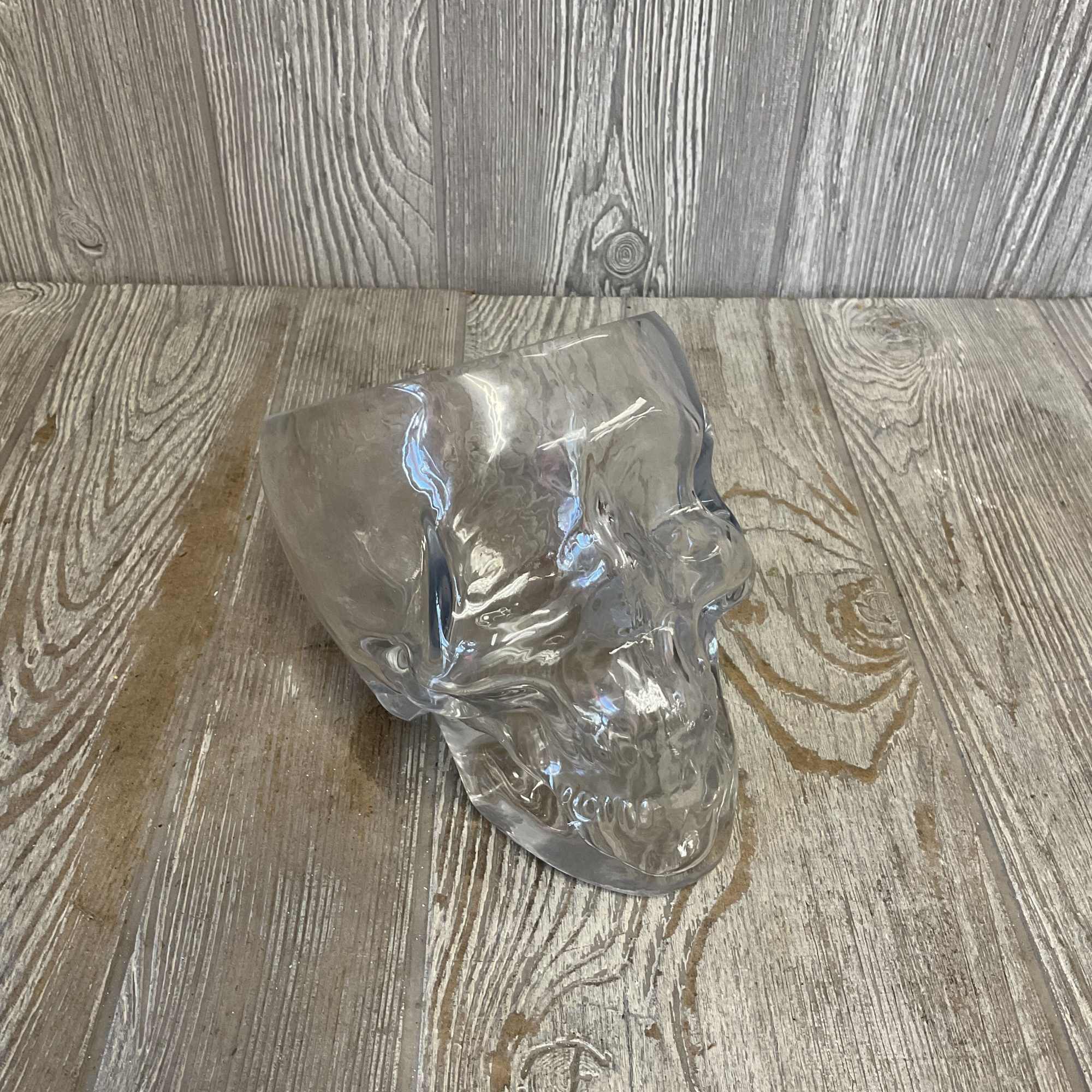 Clear glass skull-shaped vase on a wood surface