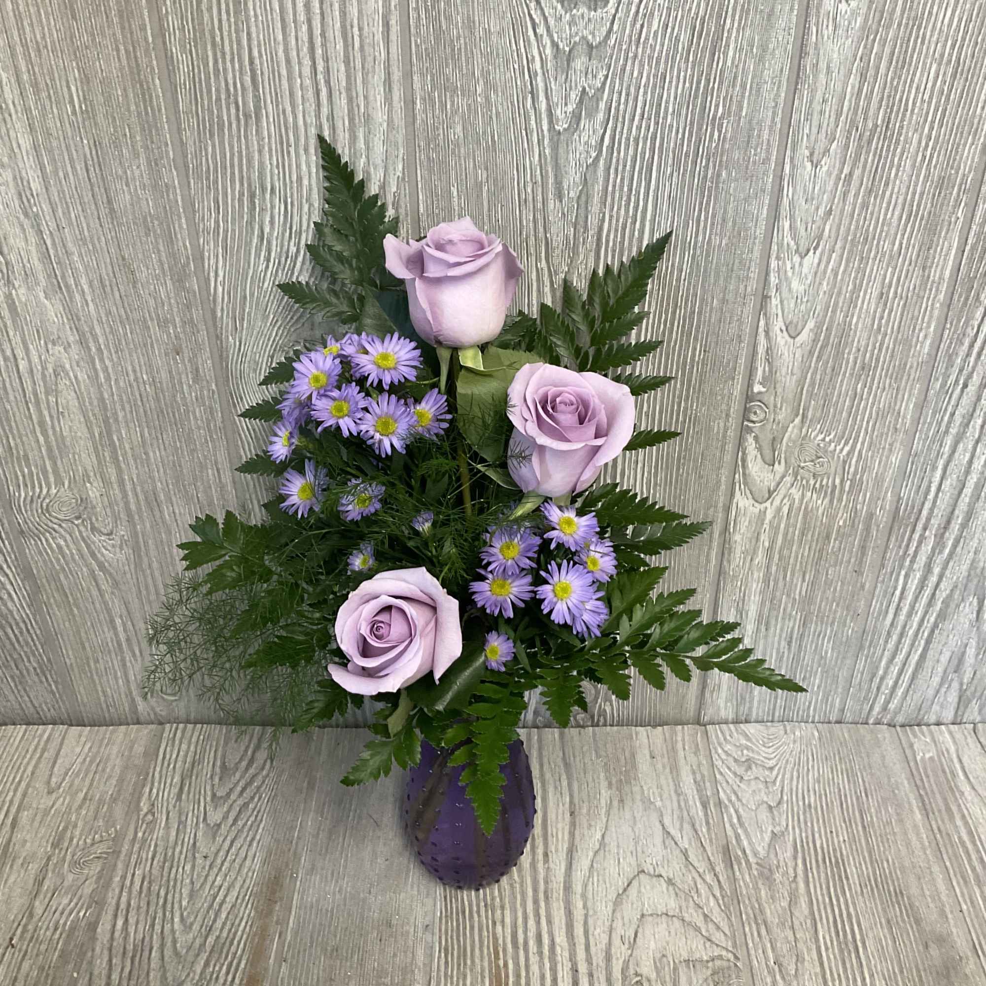Lavender roses and purple daisies in a purple vase