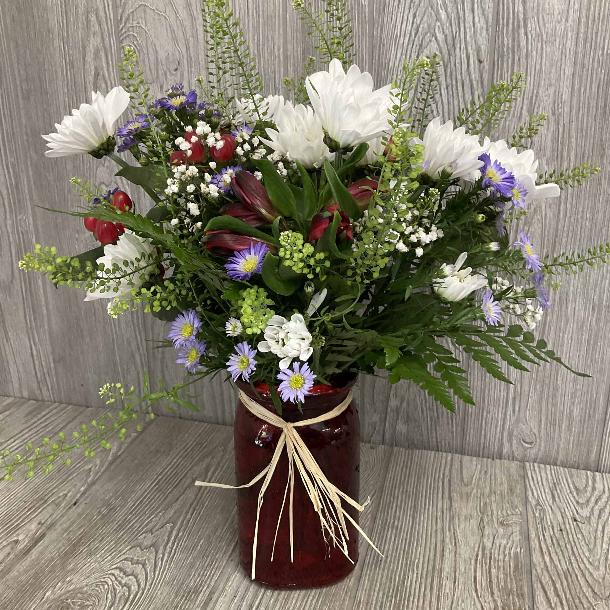 Romantic arrangement of wild flowers in a red vase.