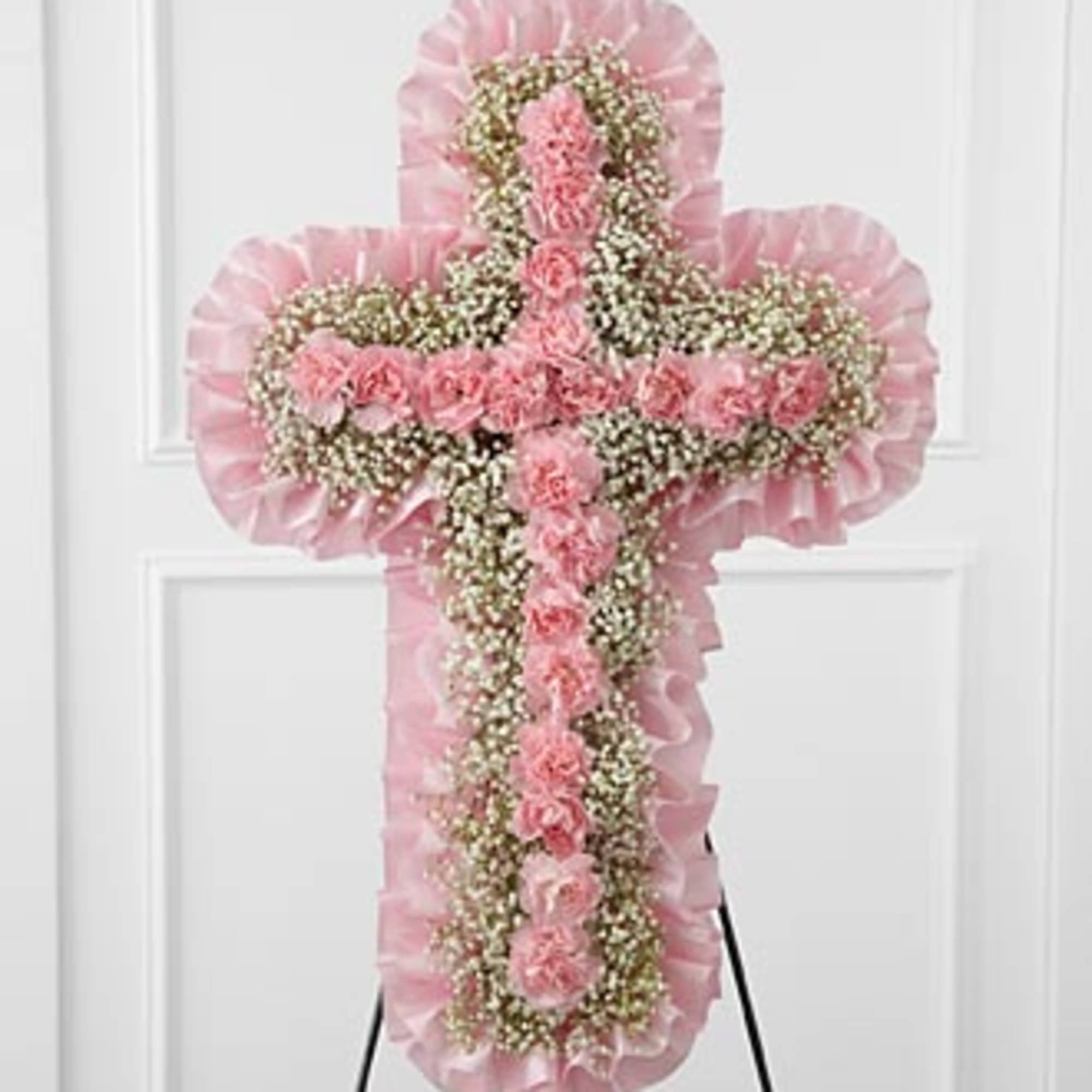 Pink floral cross on an easel with ruffled trim