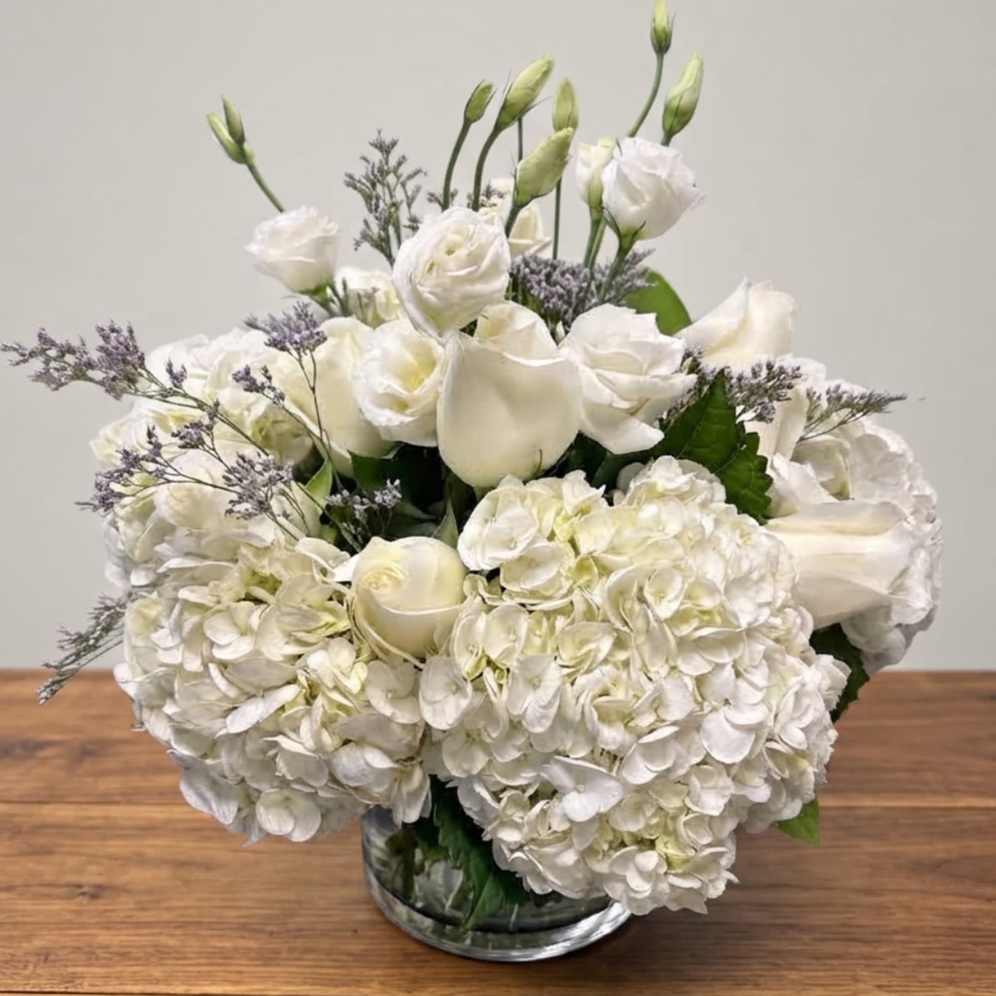 White floral arrangement with hydrangeas and roses in a glass vase