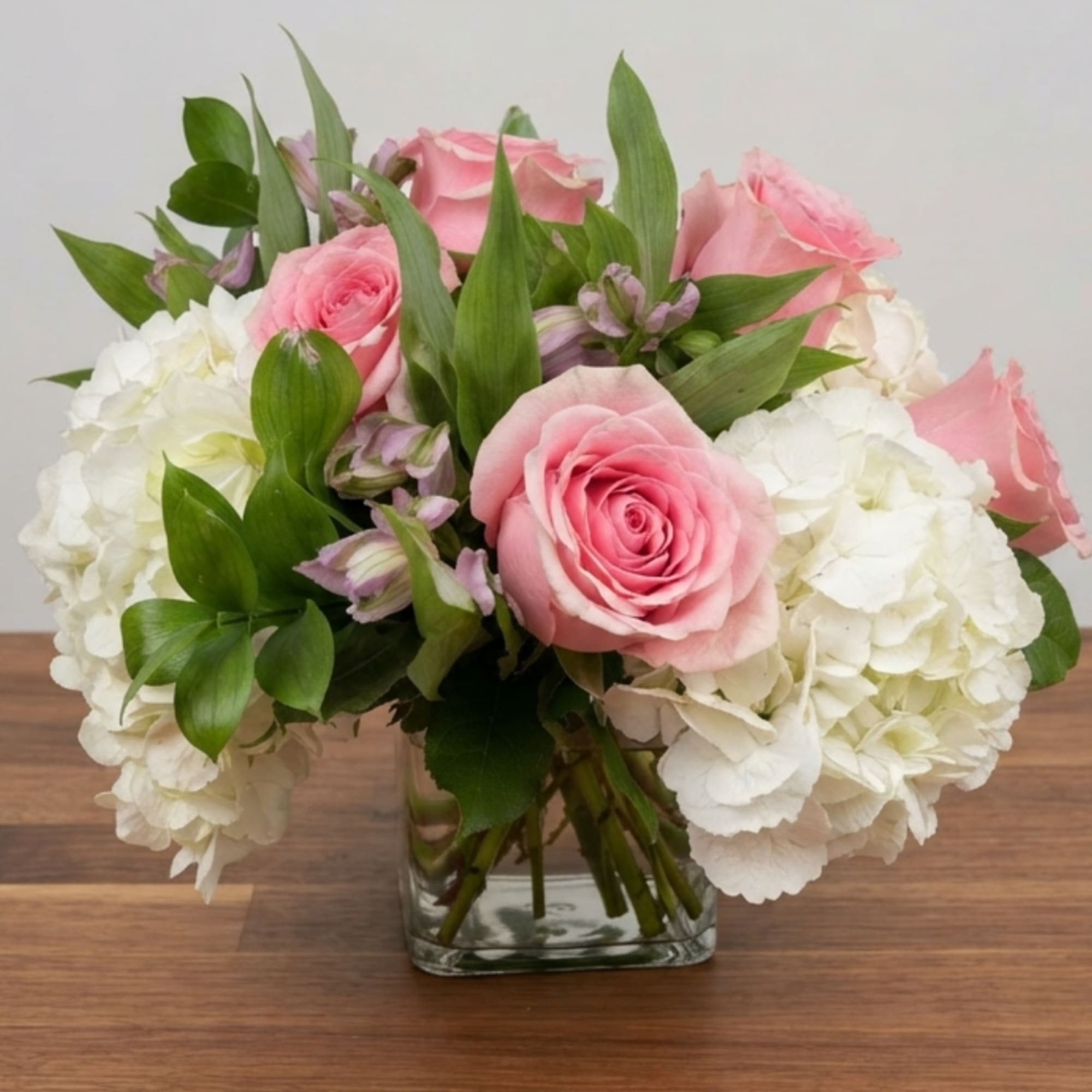Pink roses and white hydrangeas arranged in a clear glass vase