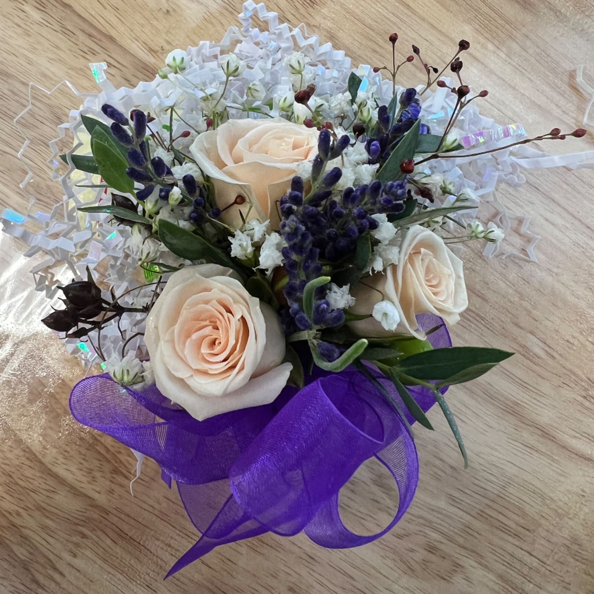 Small bouquet of cream roses with purple accents and white filler flowers