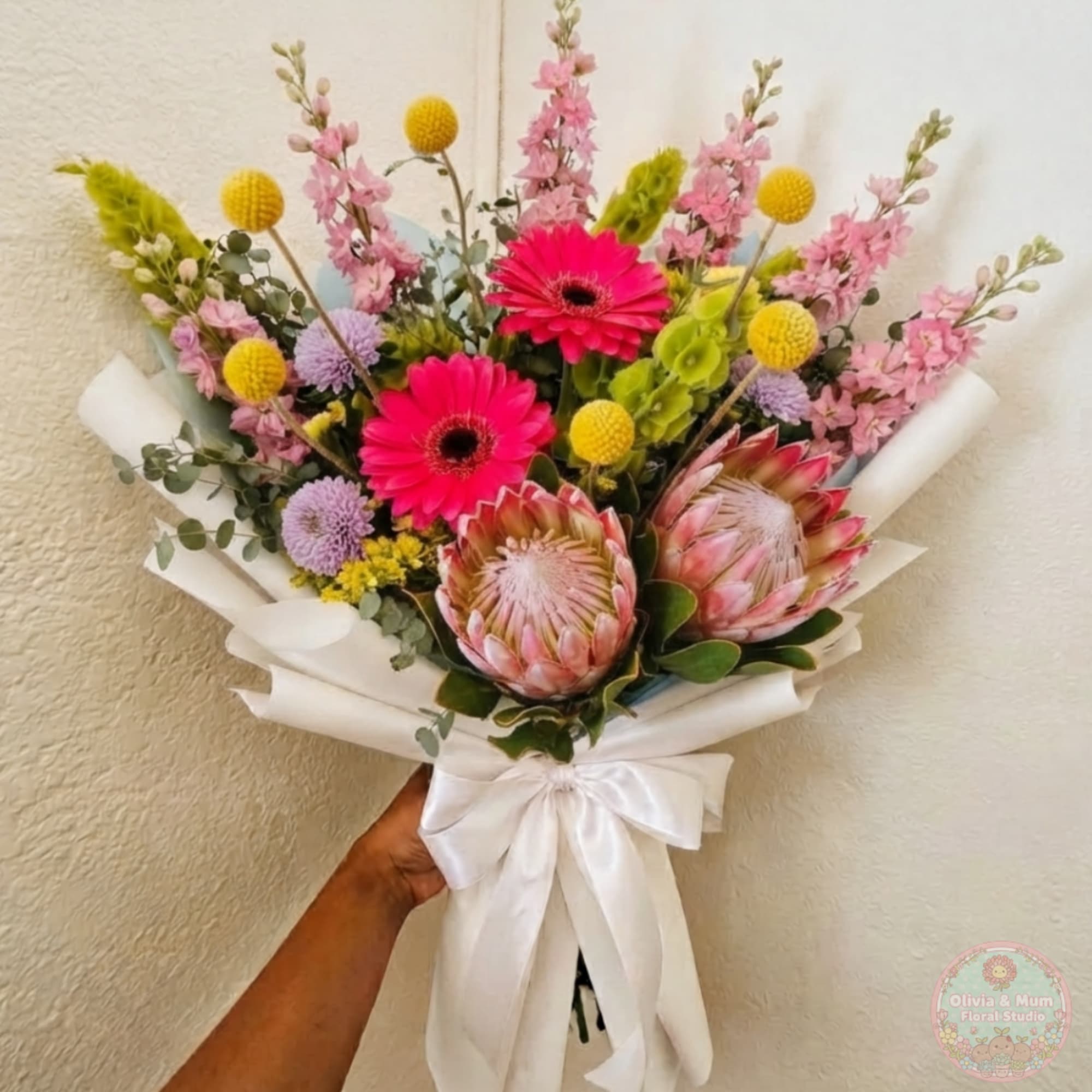 Hand-tied bouquet with pink, yellow, and lavender flowers wrapped in white paper