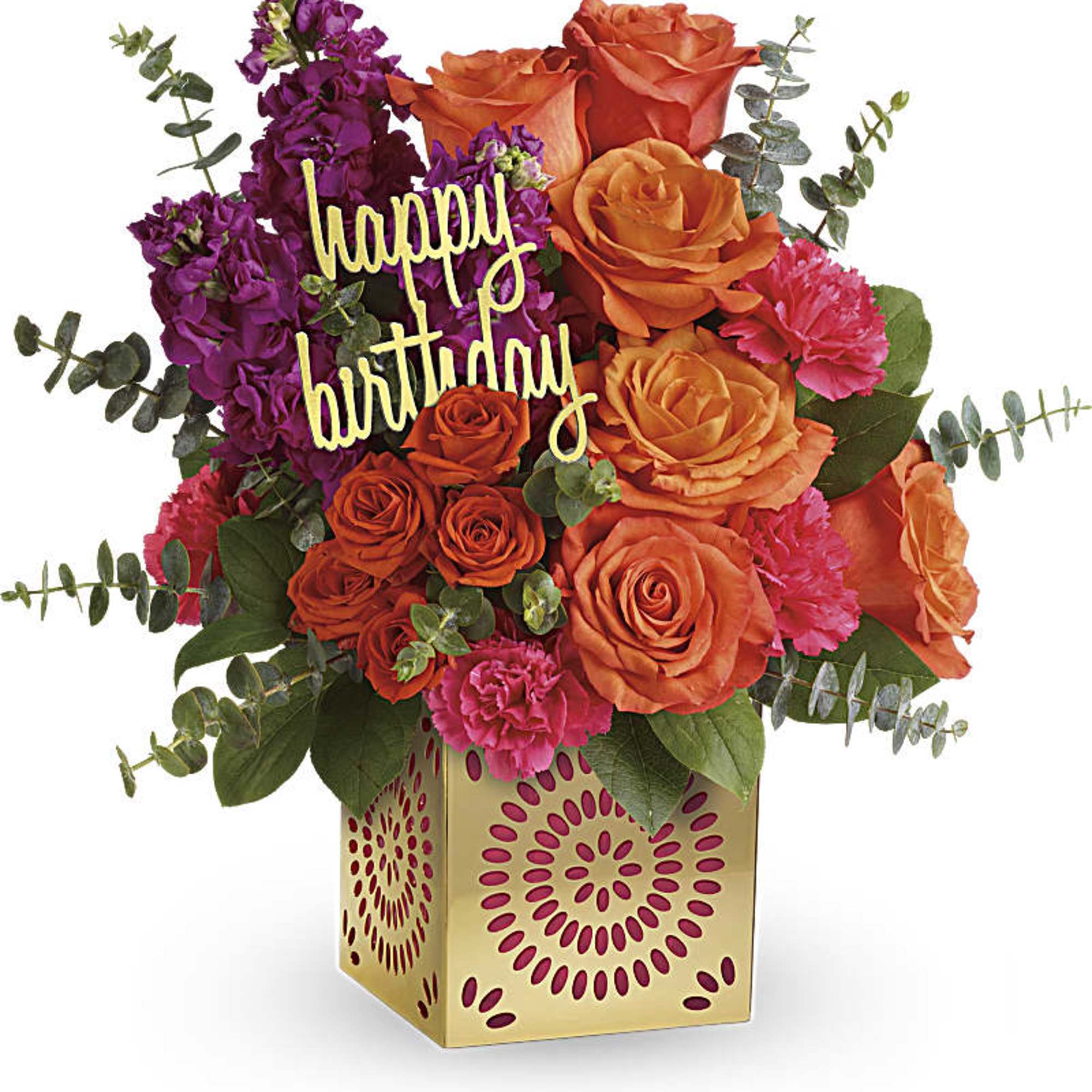 Bright orange roses, pink carnations, and purple flowers in a gold cube vase with happy birthday pick