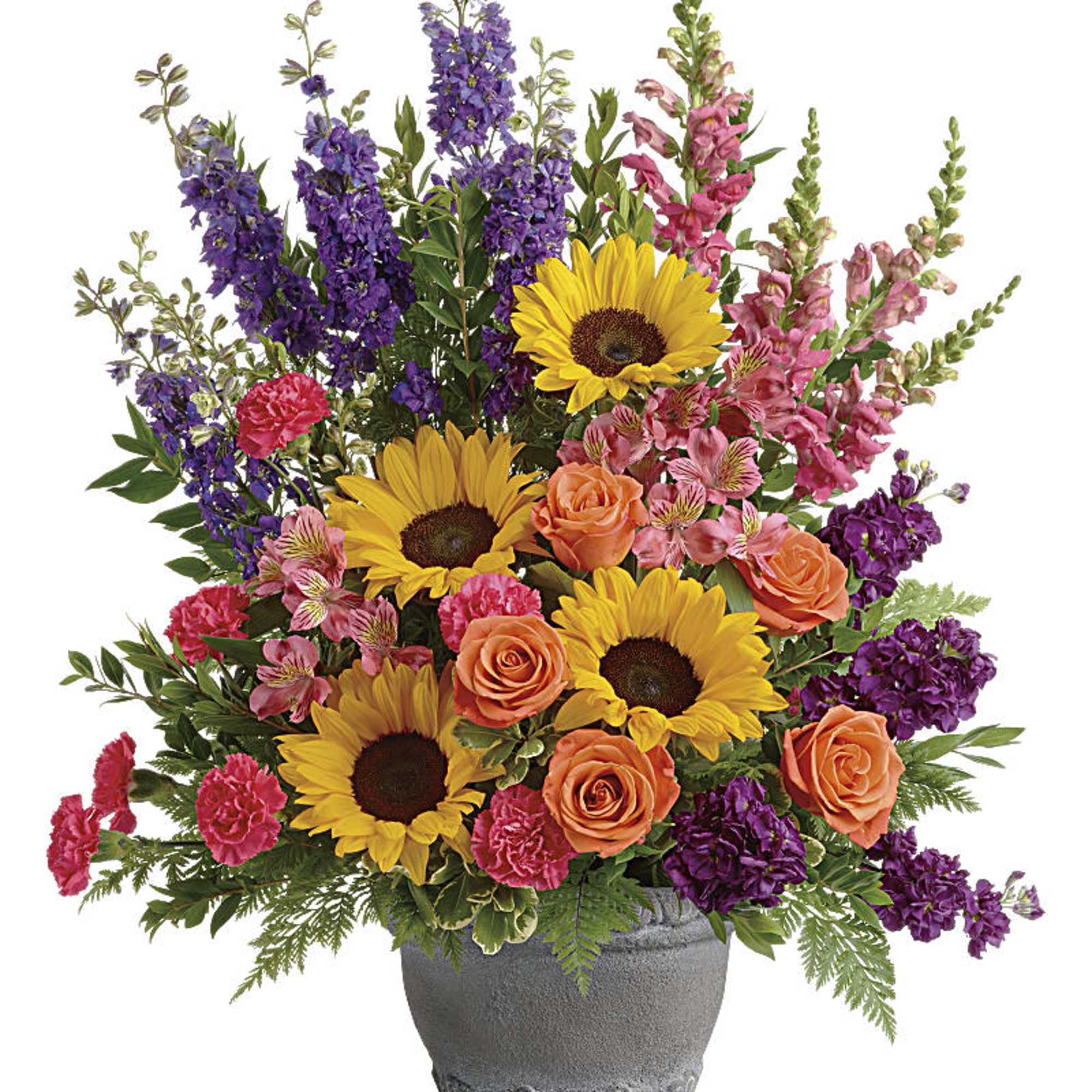 Tall mixed arrangement with sunflowers, orange roses, pink carnations and purple flowers in a gray pot