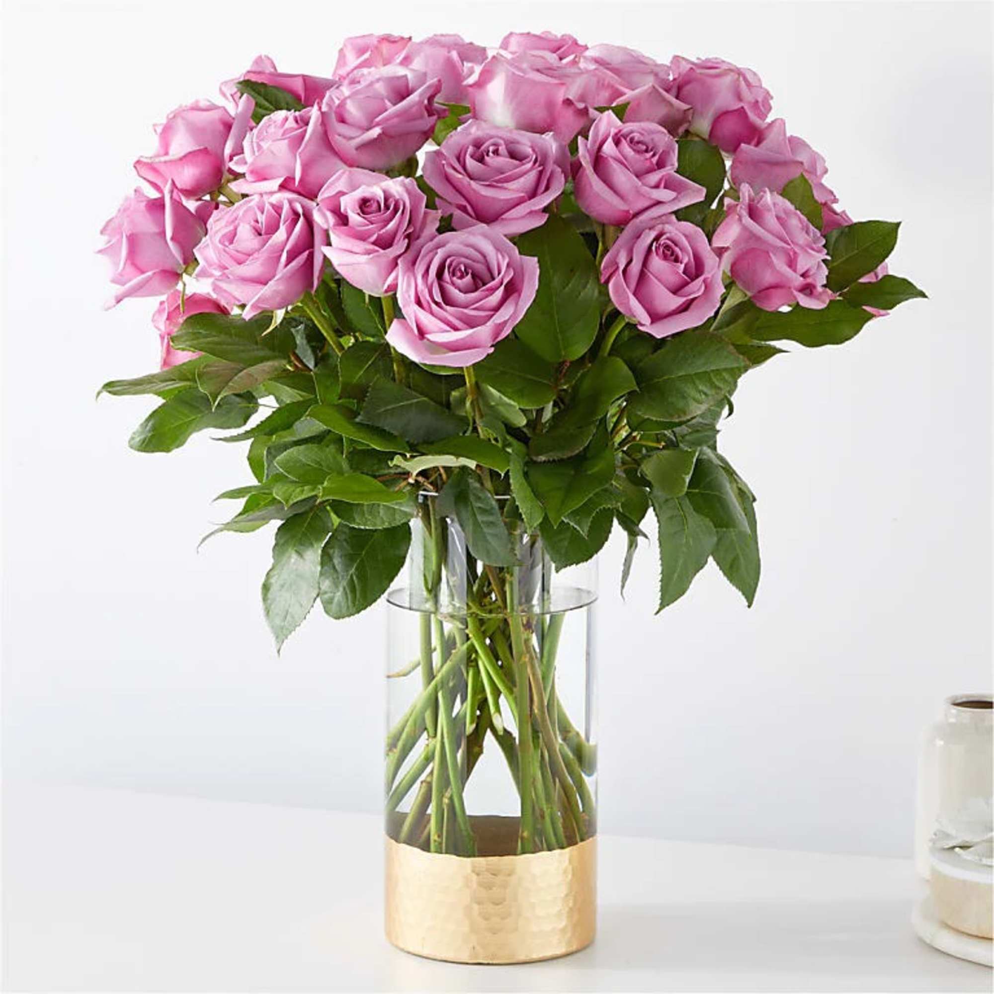 Tall arrangement of pink roses in a clear glass vase with a gold metal base