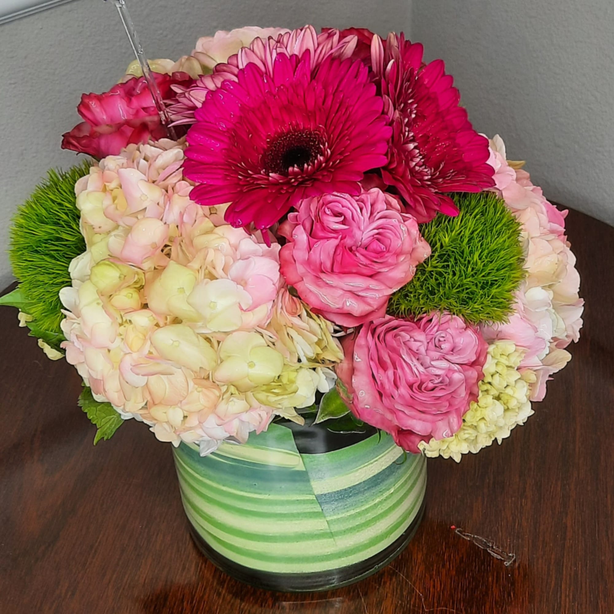 Pink and cream floral arrangement in a striped green vase