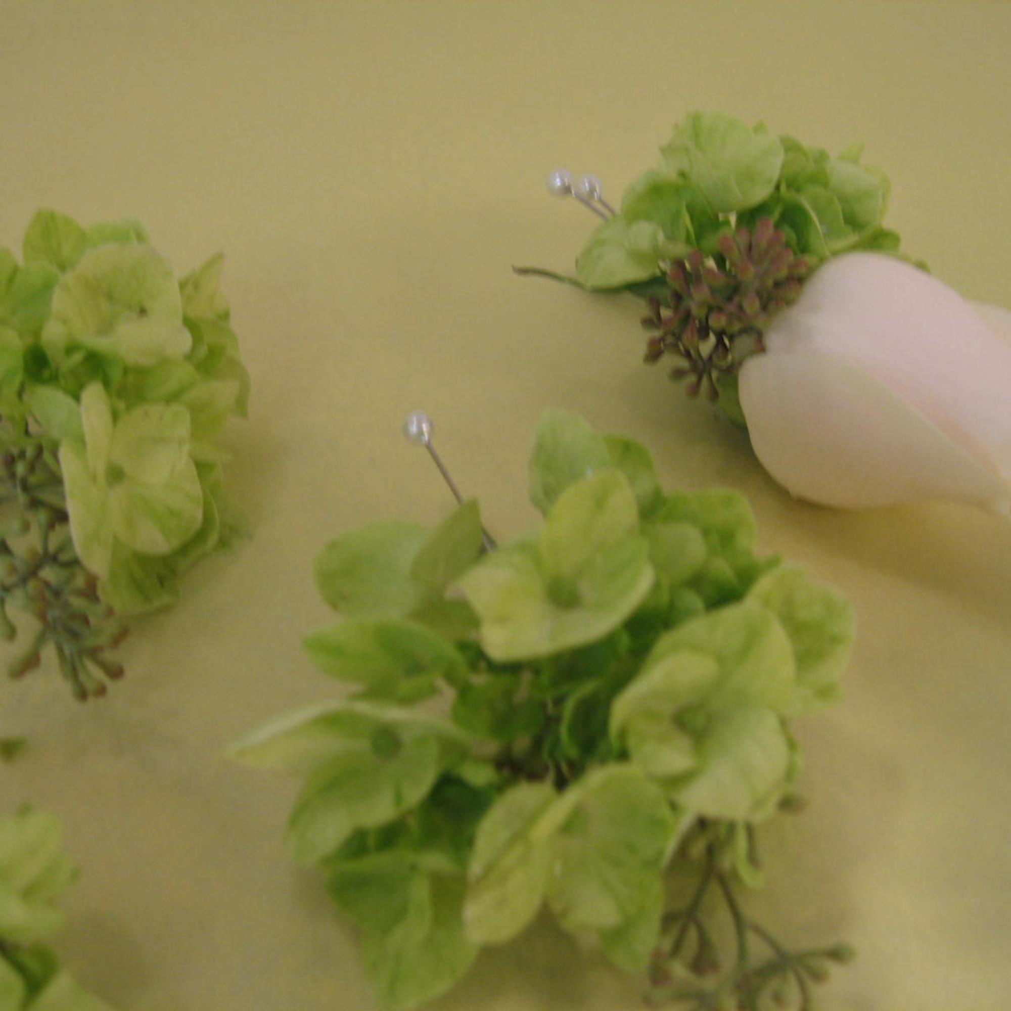 Green floral boutonnieres with one white rose bud