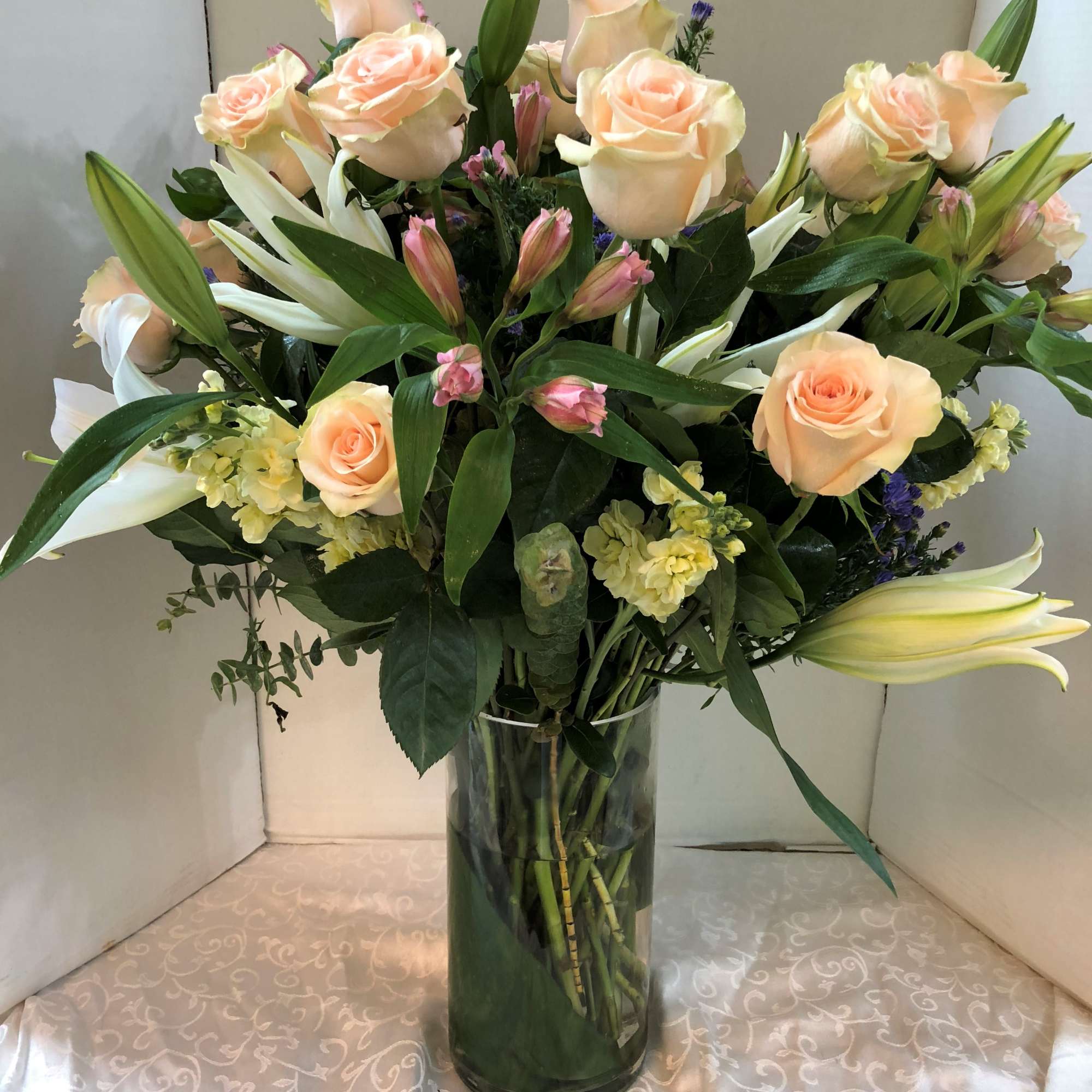 Bouquet of peach roses and white lilies in a glass vase