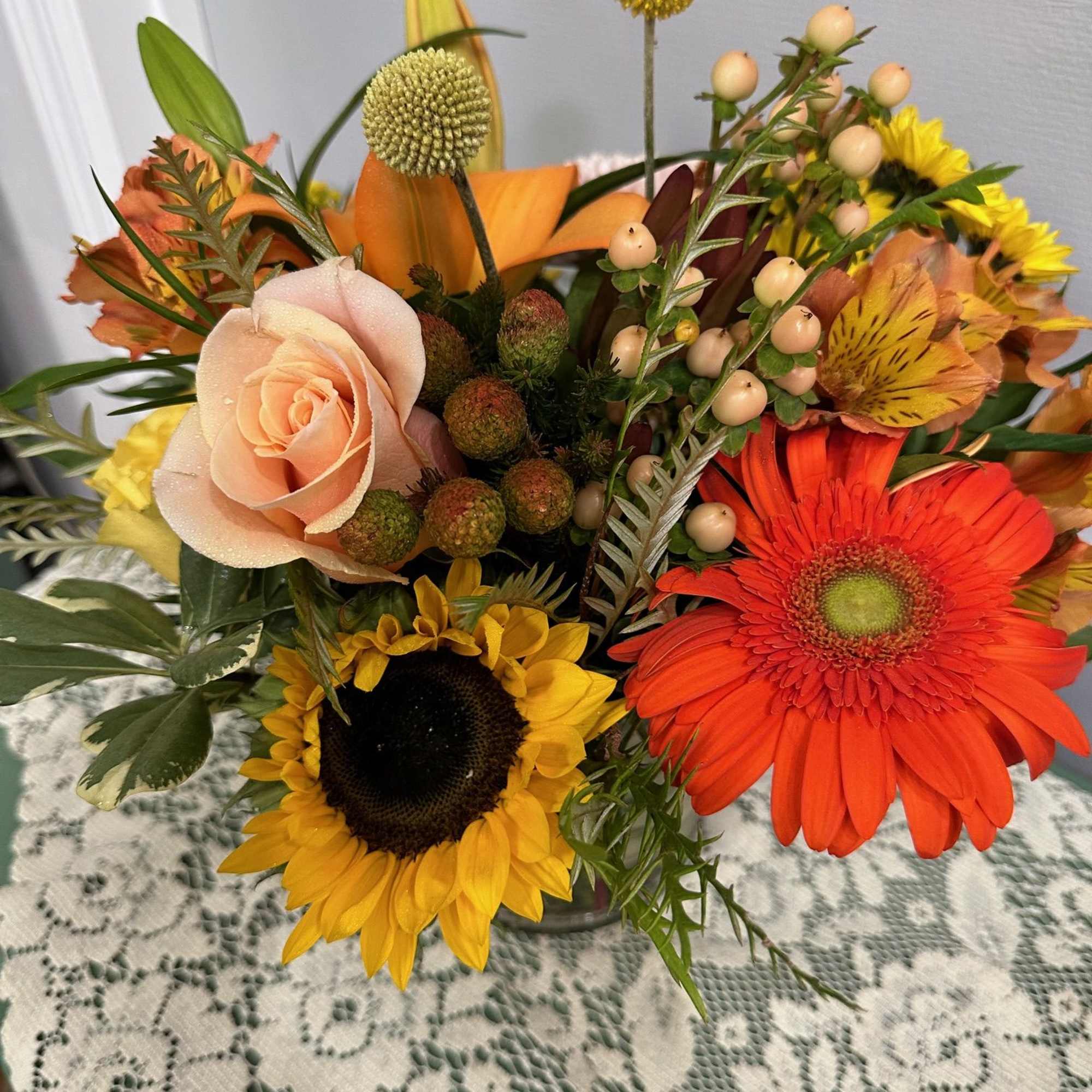 Mixed bouquet with sunflowers, gerbera daisies, and a peach rose in a vase