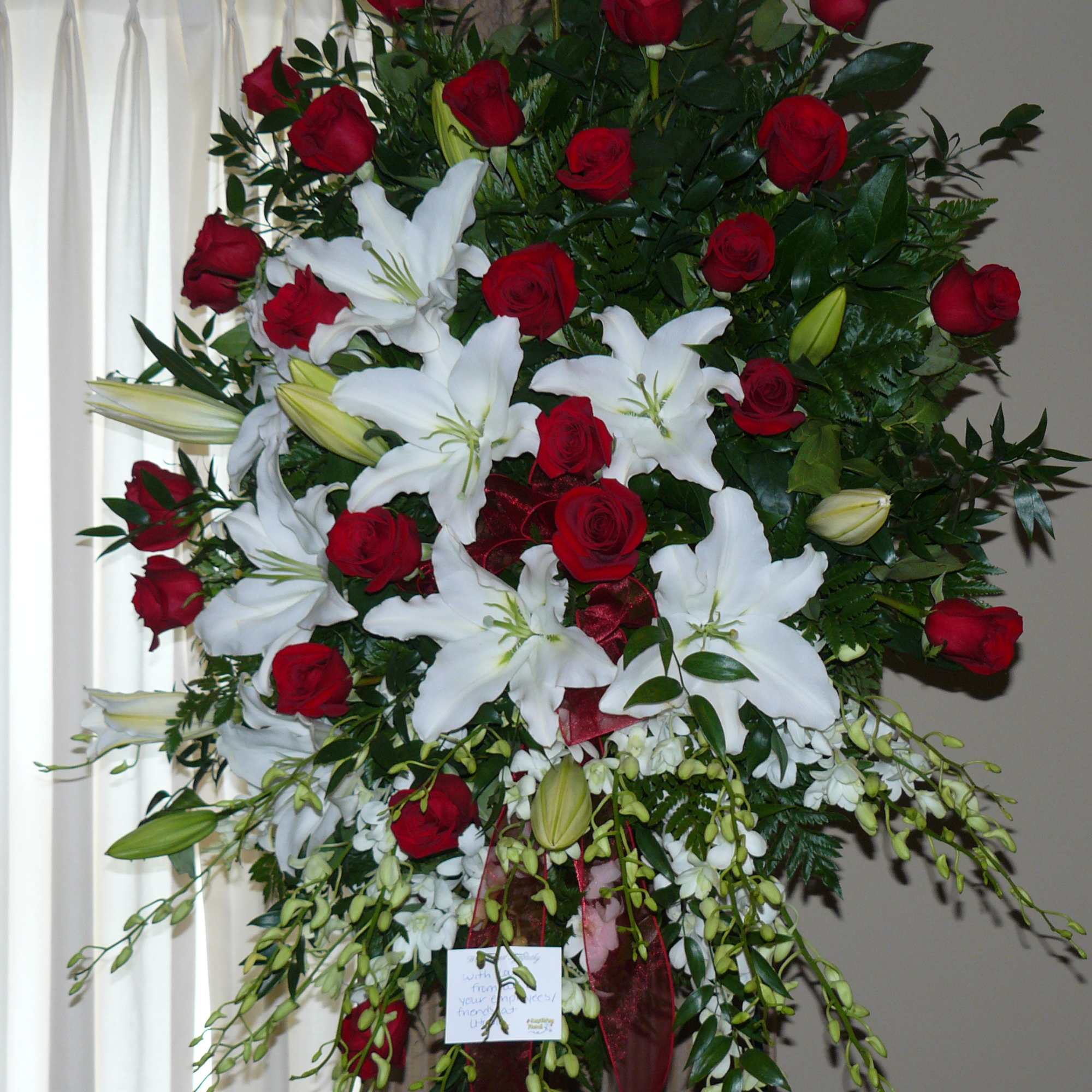 Standing spray of red roses and white lilies with greenery