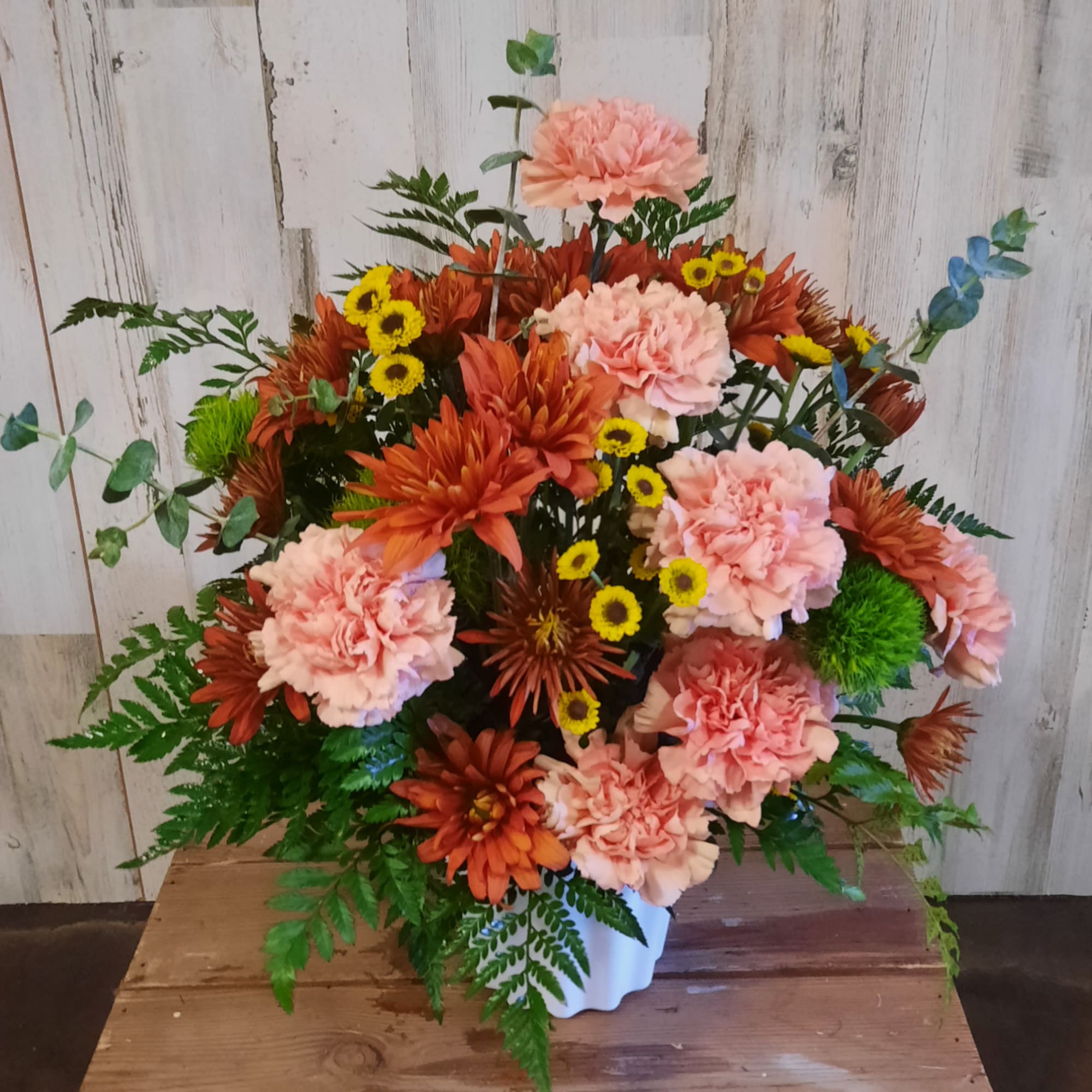 Pink and orange floral arrangement in a white vase