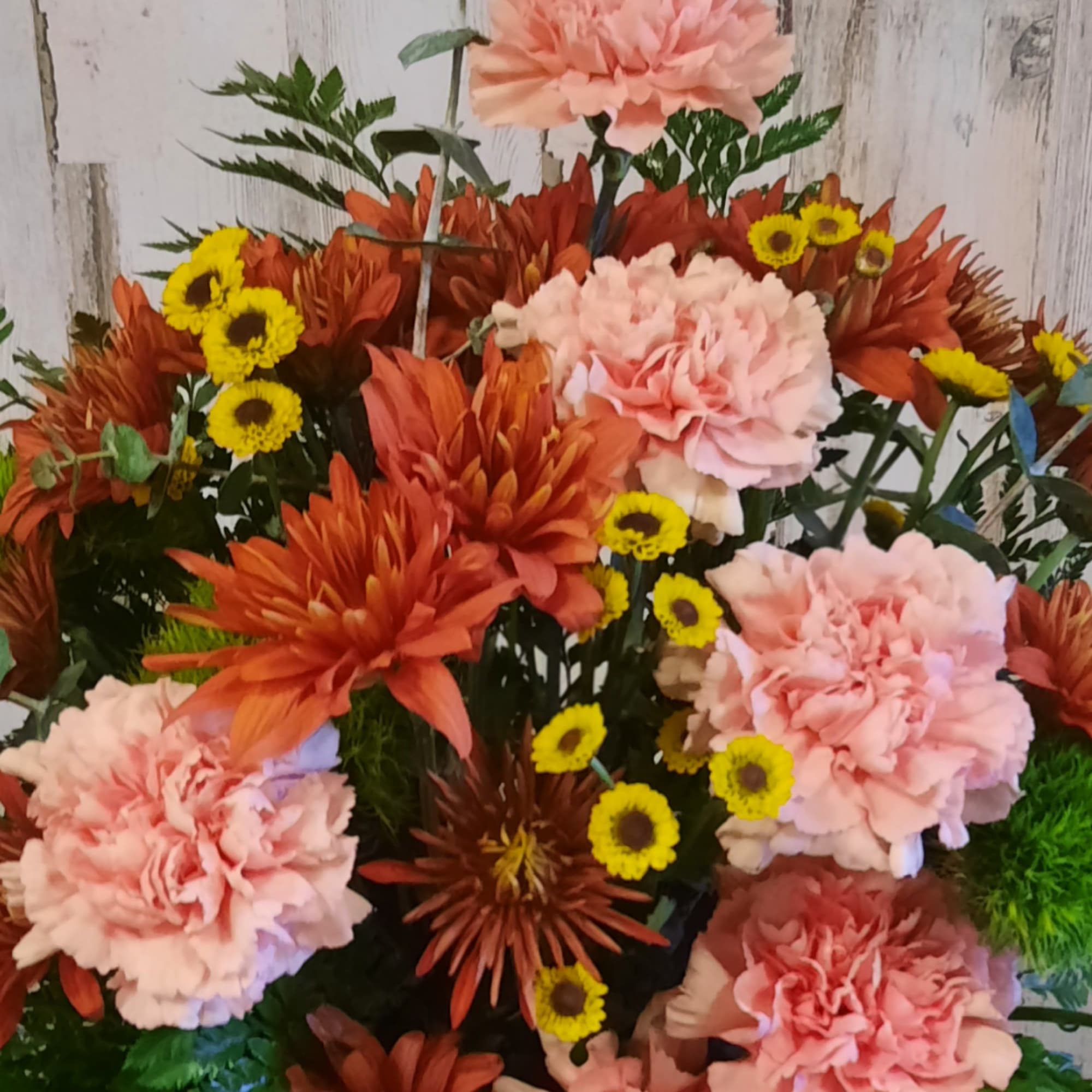 Bouquet of pink carnations, orange chrysanthemums, and small yellow daisies