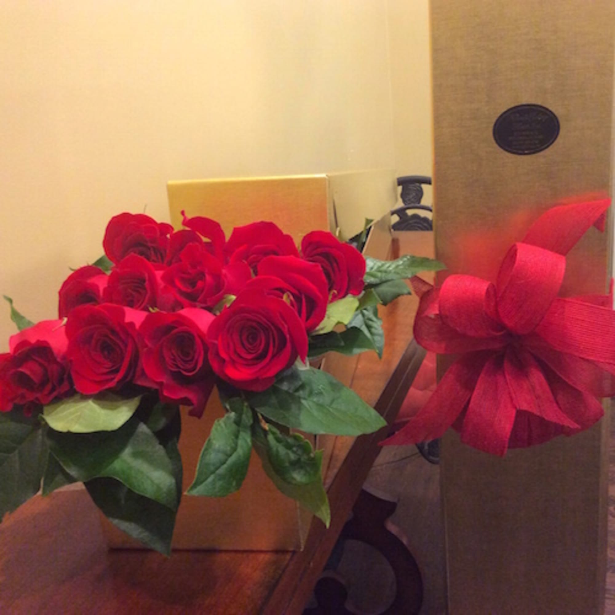Bouquet of red roses with a red ribbon bow on a gift box