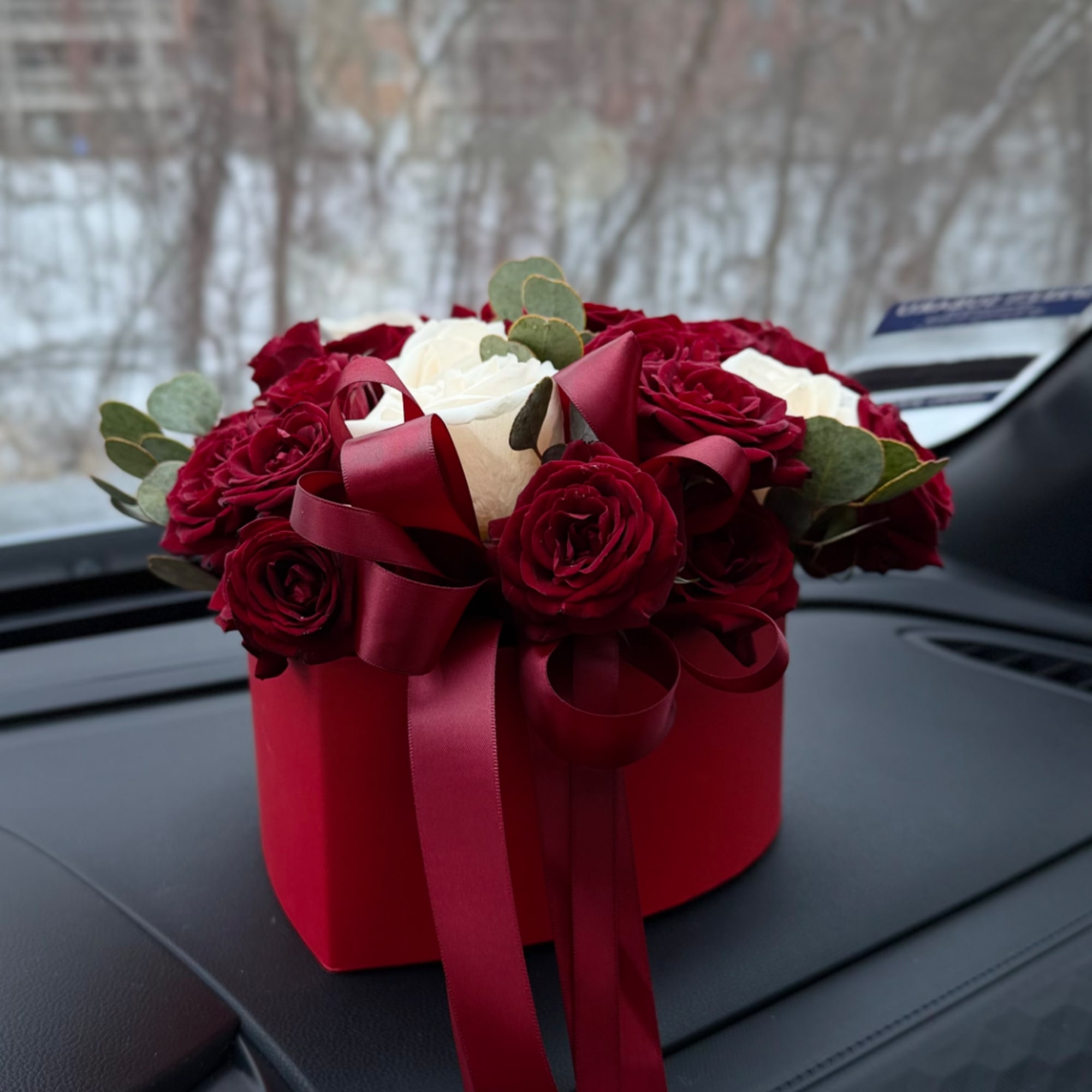 Red and white roses in a red gift box with ribbon