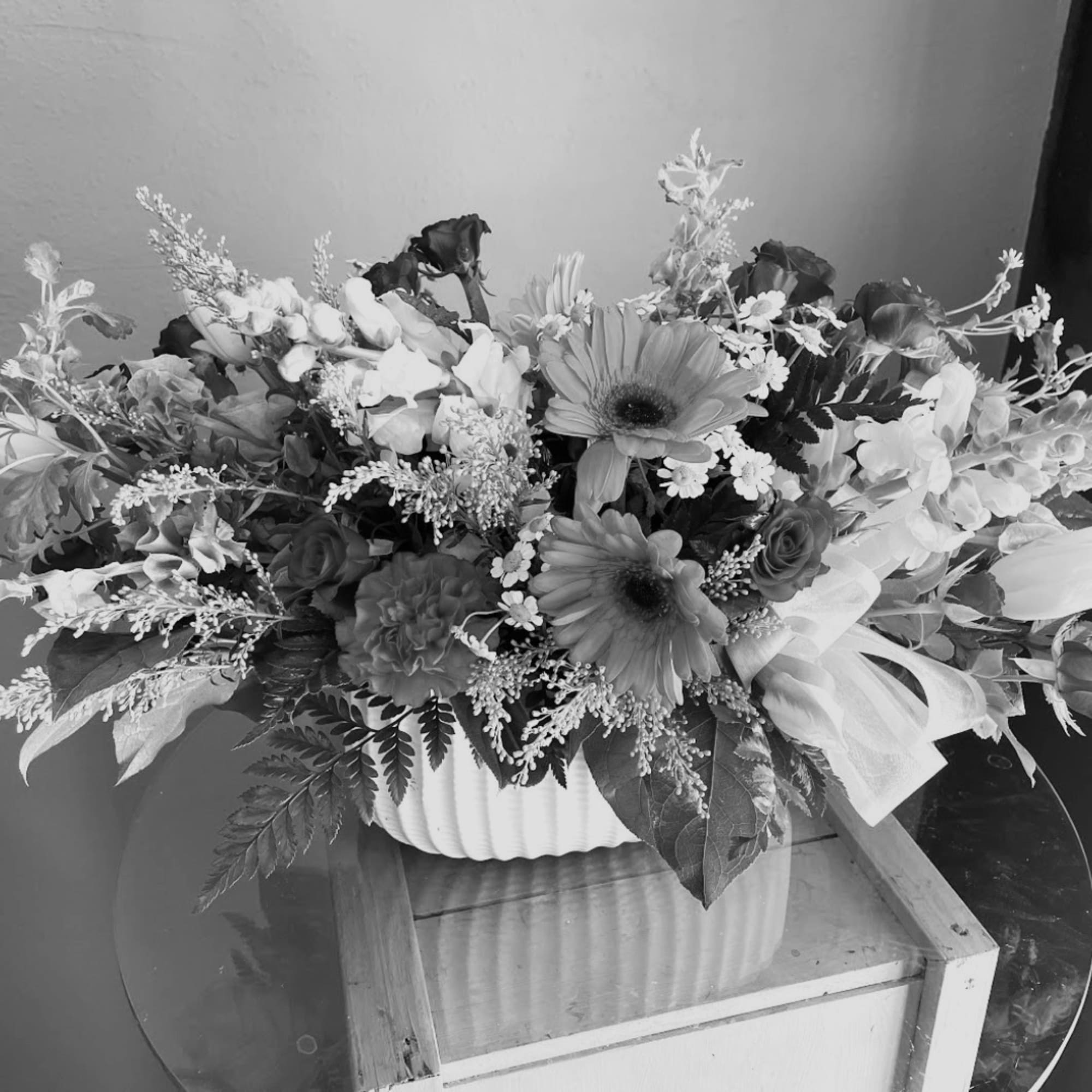 Large mixed flower arrangement in a white ribbed container