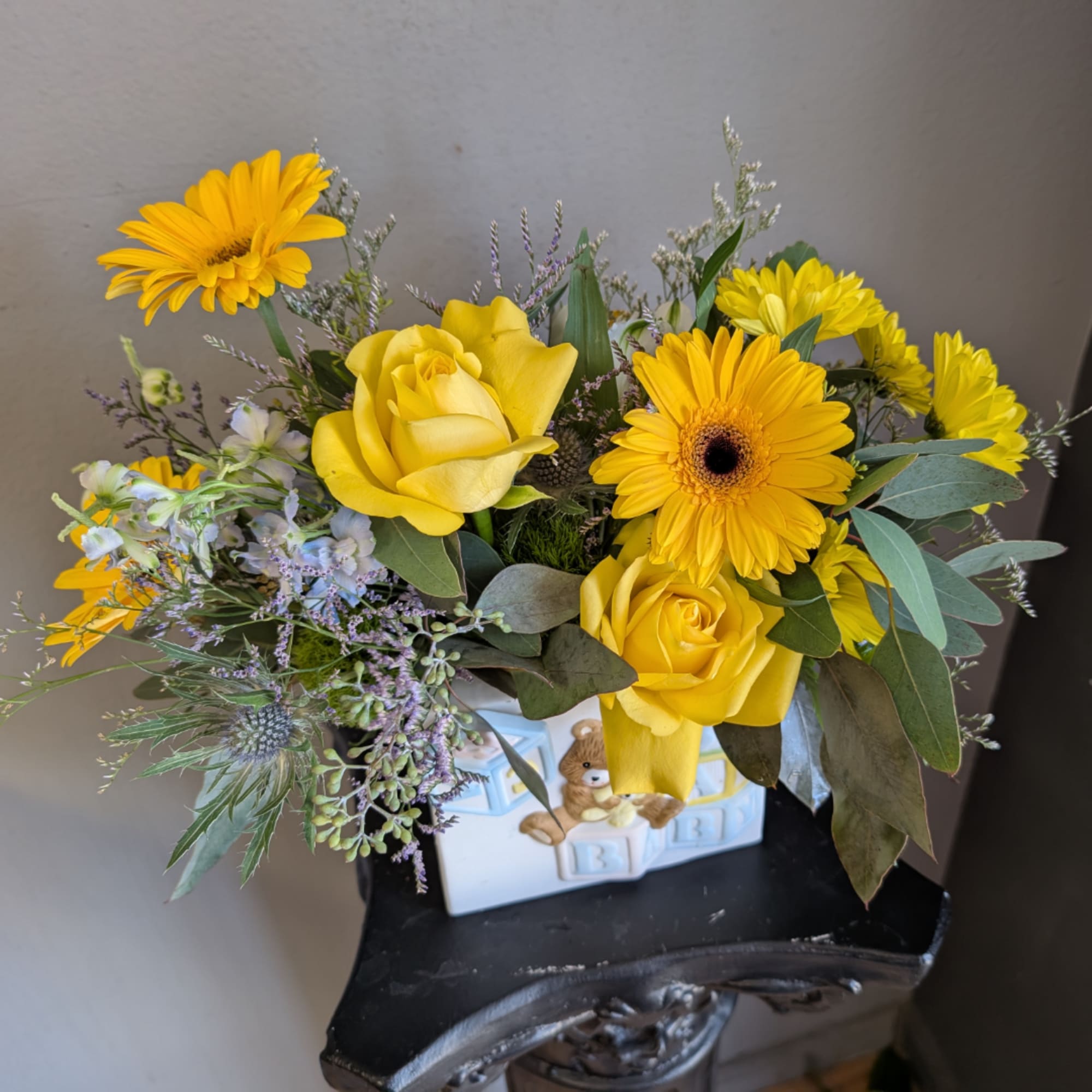 Yellow roses and gerbera daisies in a decorative ceramic container