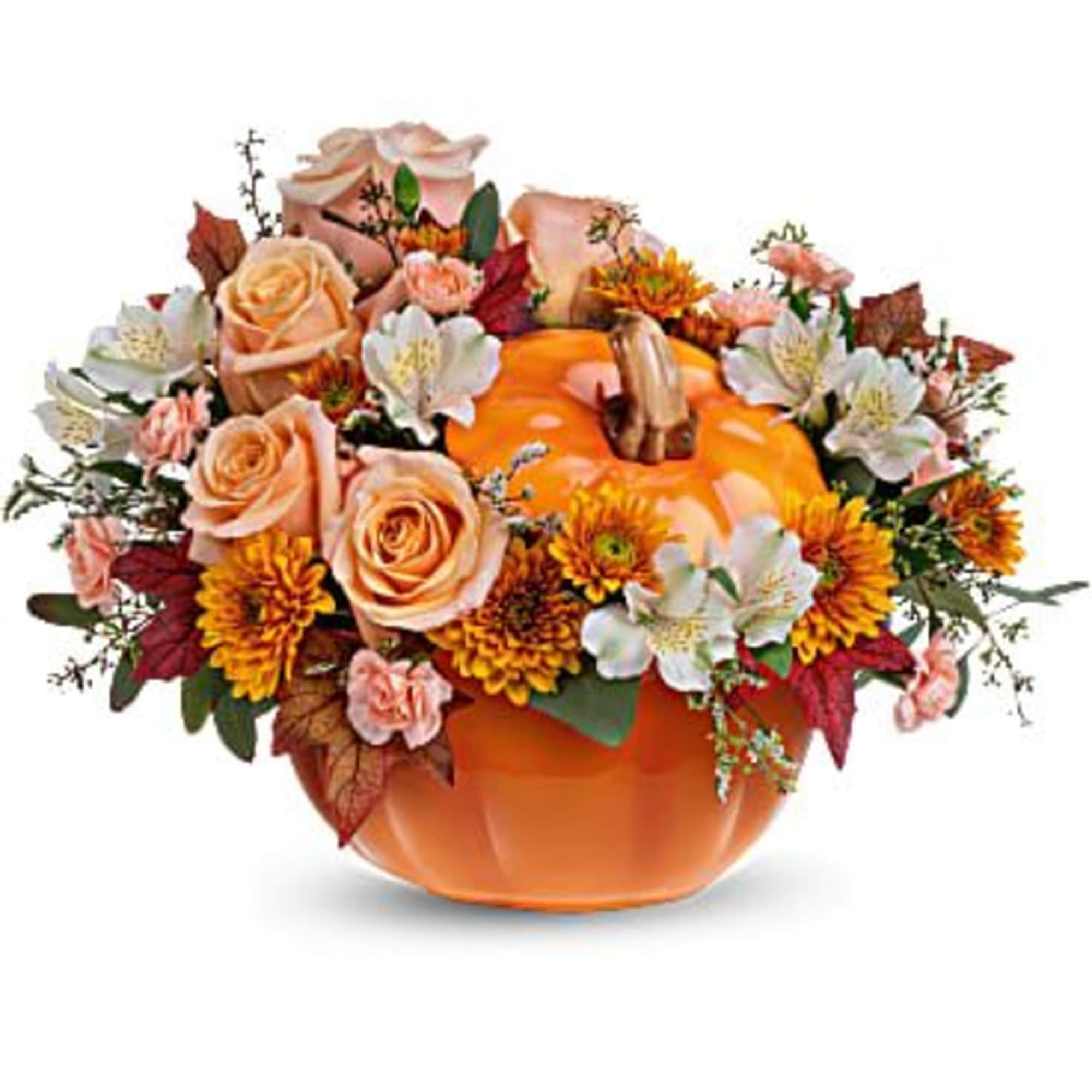 Low arrangement of peach roses, orange mums, and white blooms in an orange pumpkin container