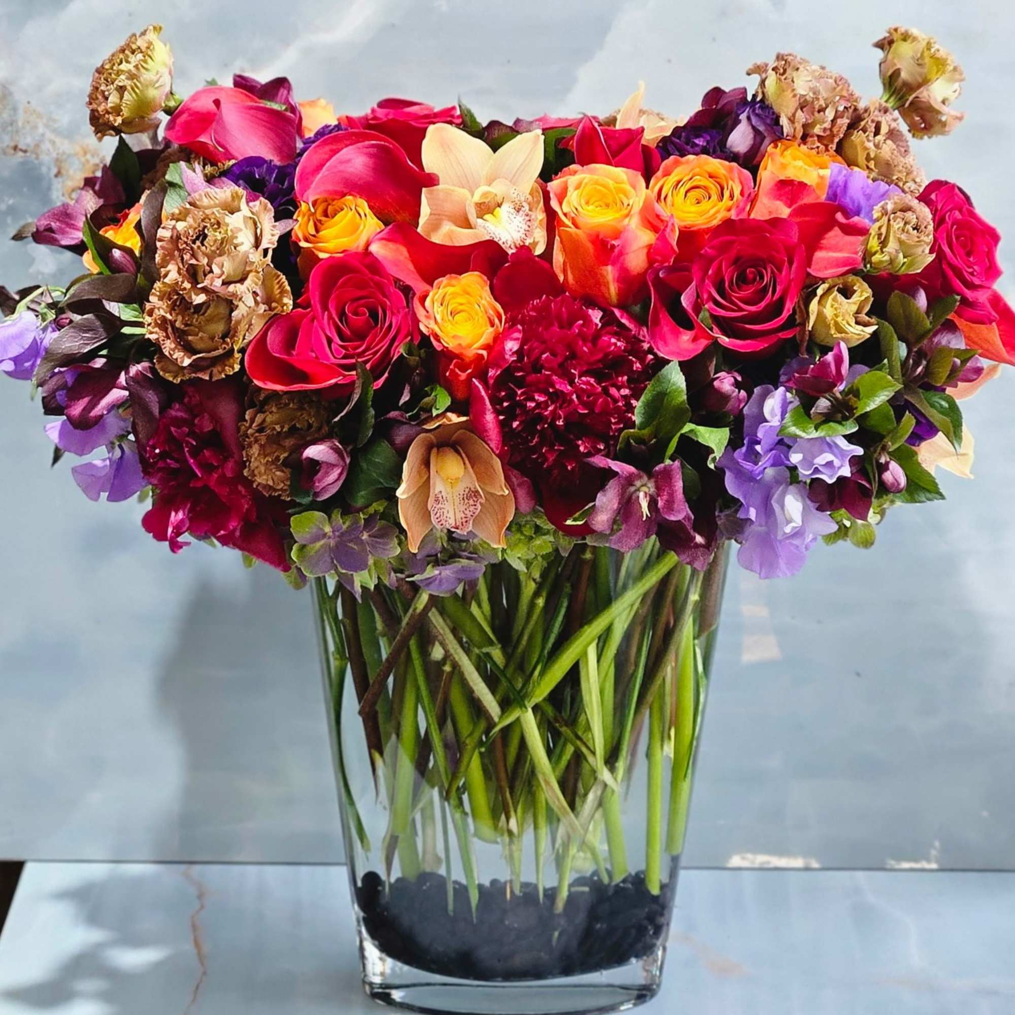 Premium Roses, Lisianthus, Tulips, Ranunculus, and more in glass vase and white