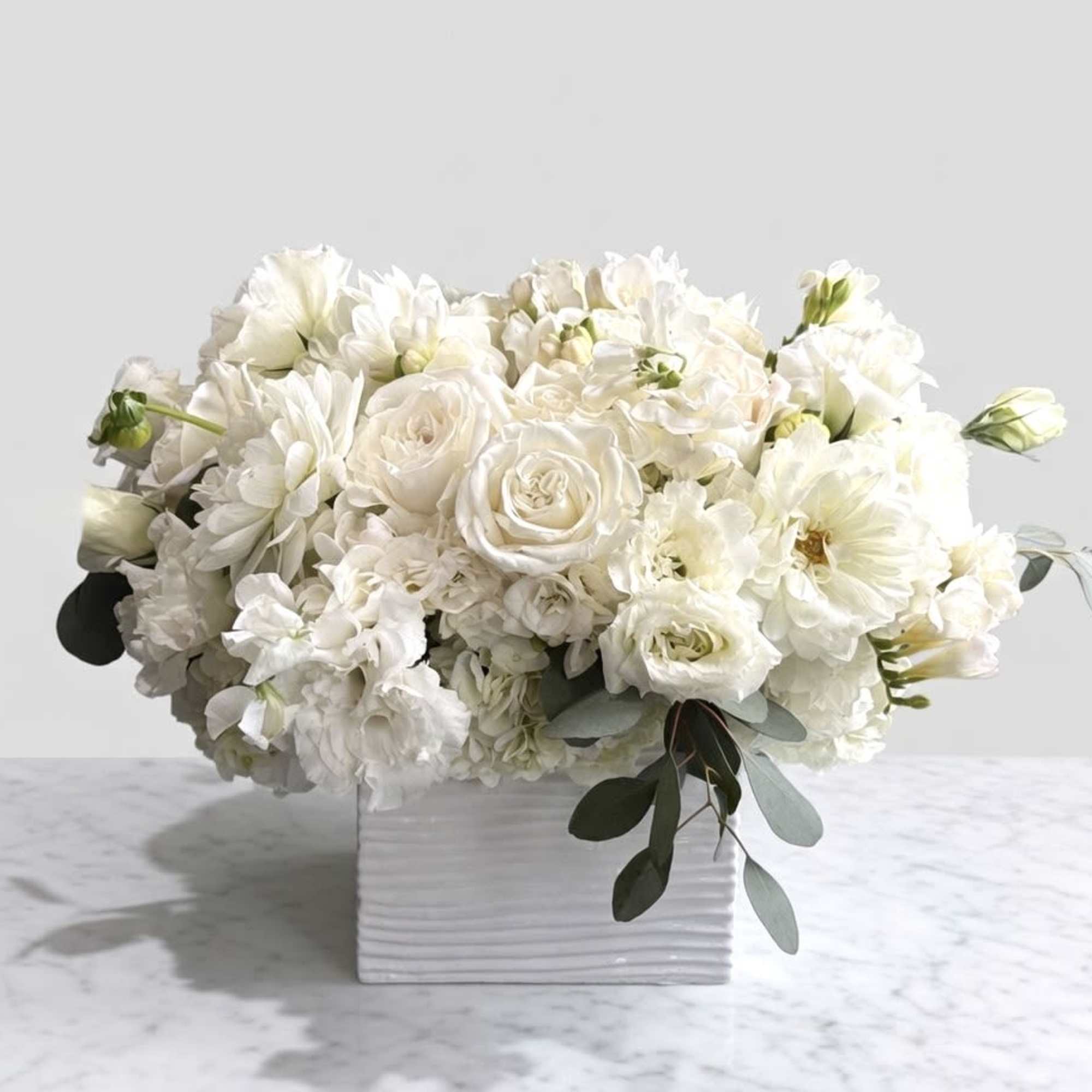 White floral arrangement in a square white vase