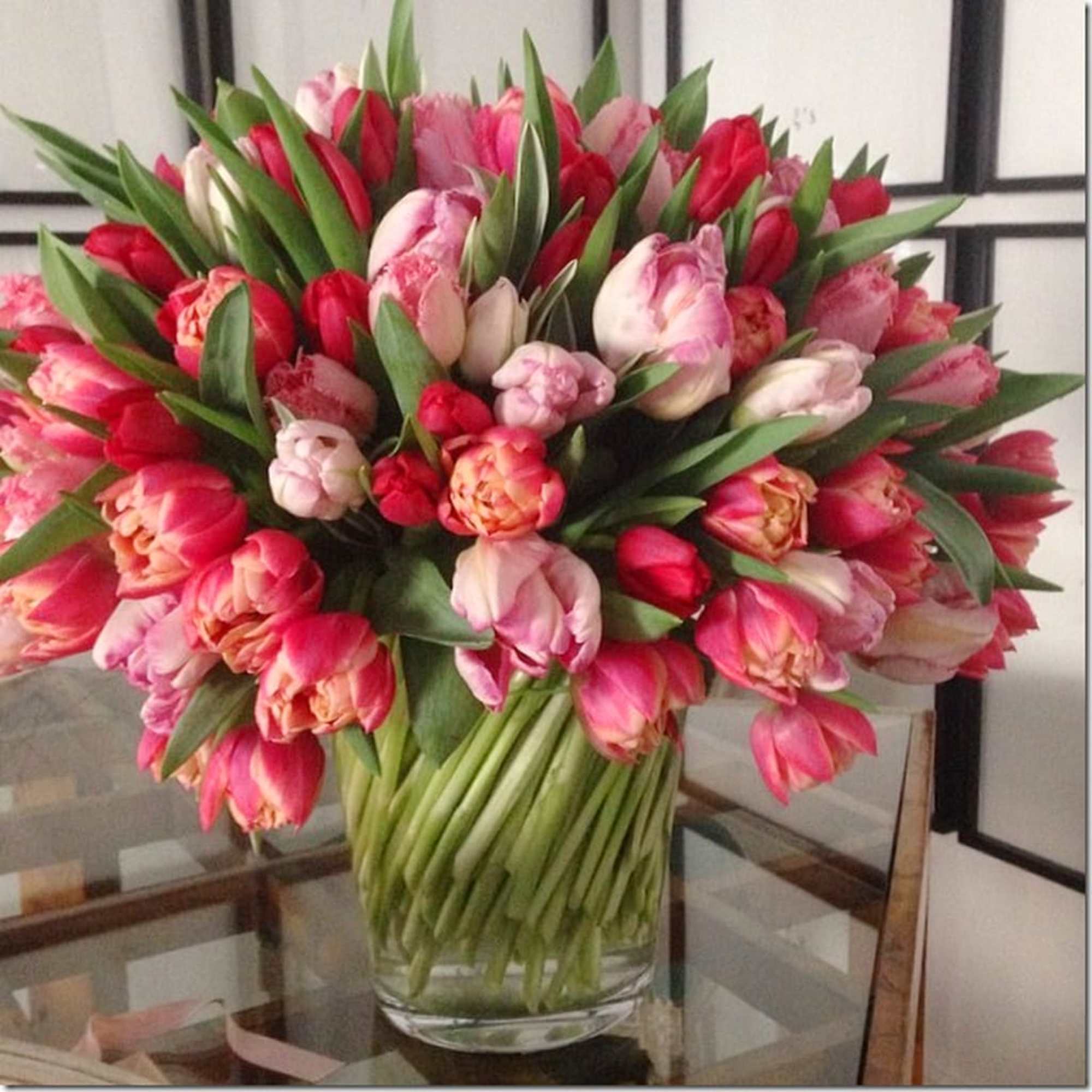 Large bouquet of pink and red tulips in a clear glass vase