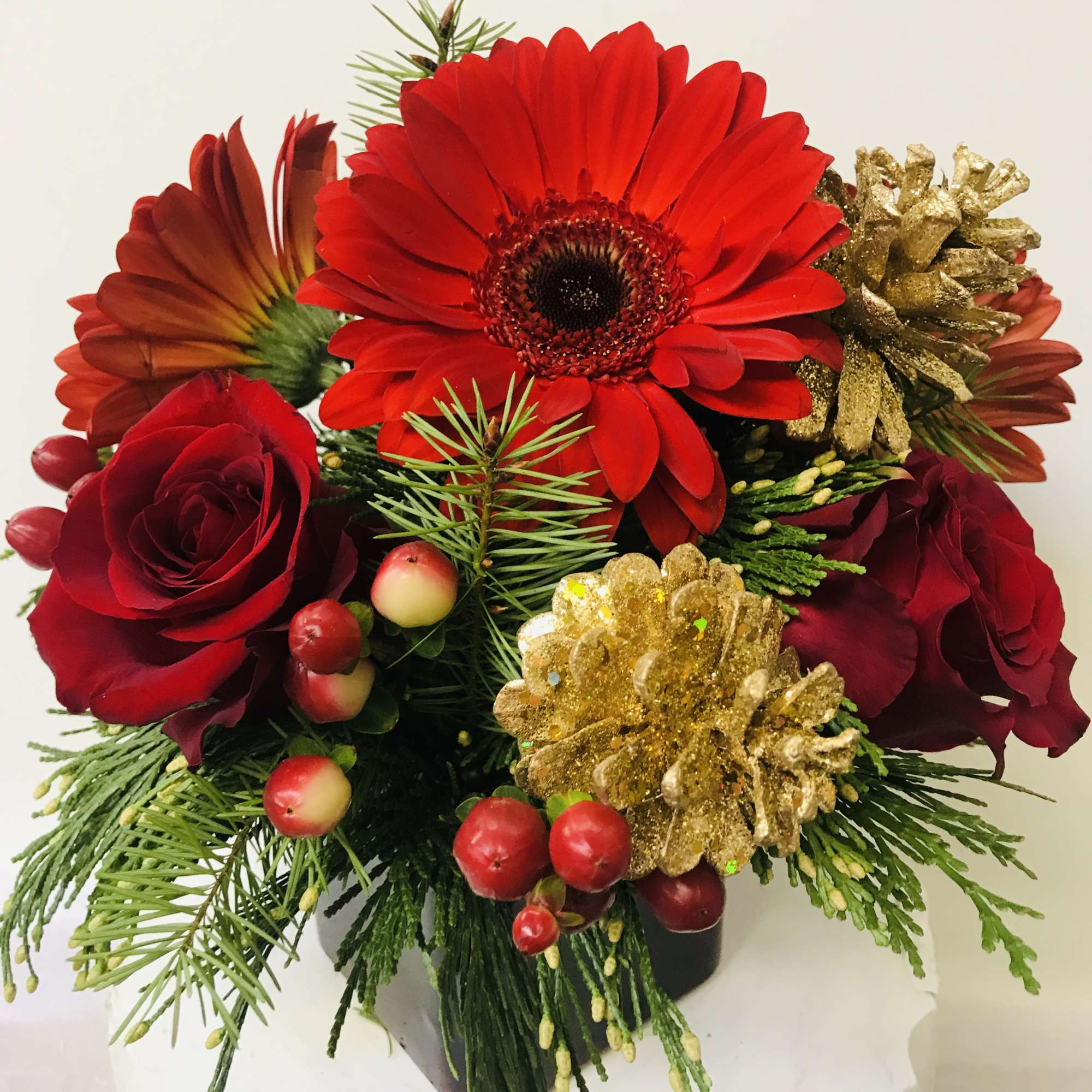 red glass vase with a Xmas greenery red Gerber, red roses and