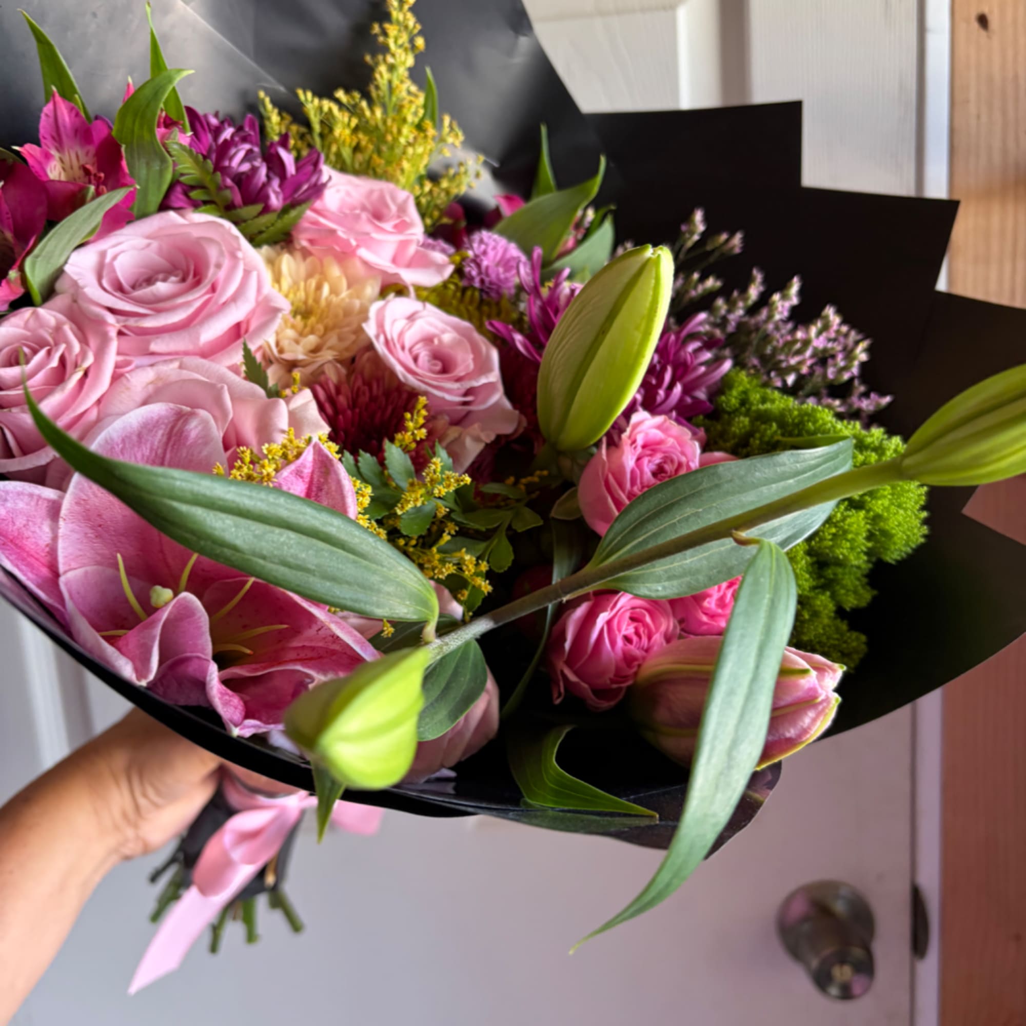 Pink bouquet with roses and lilies wrapped in black paper