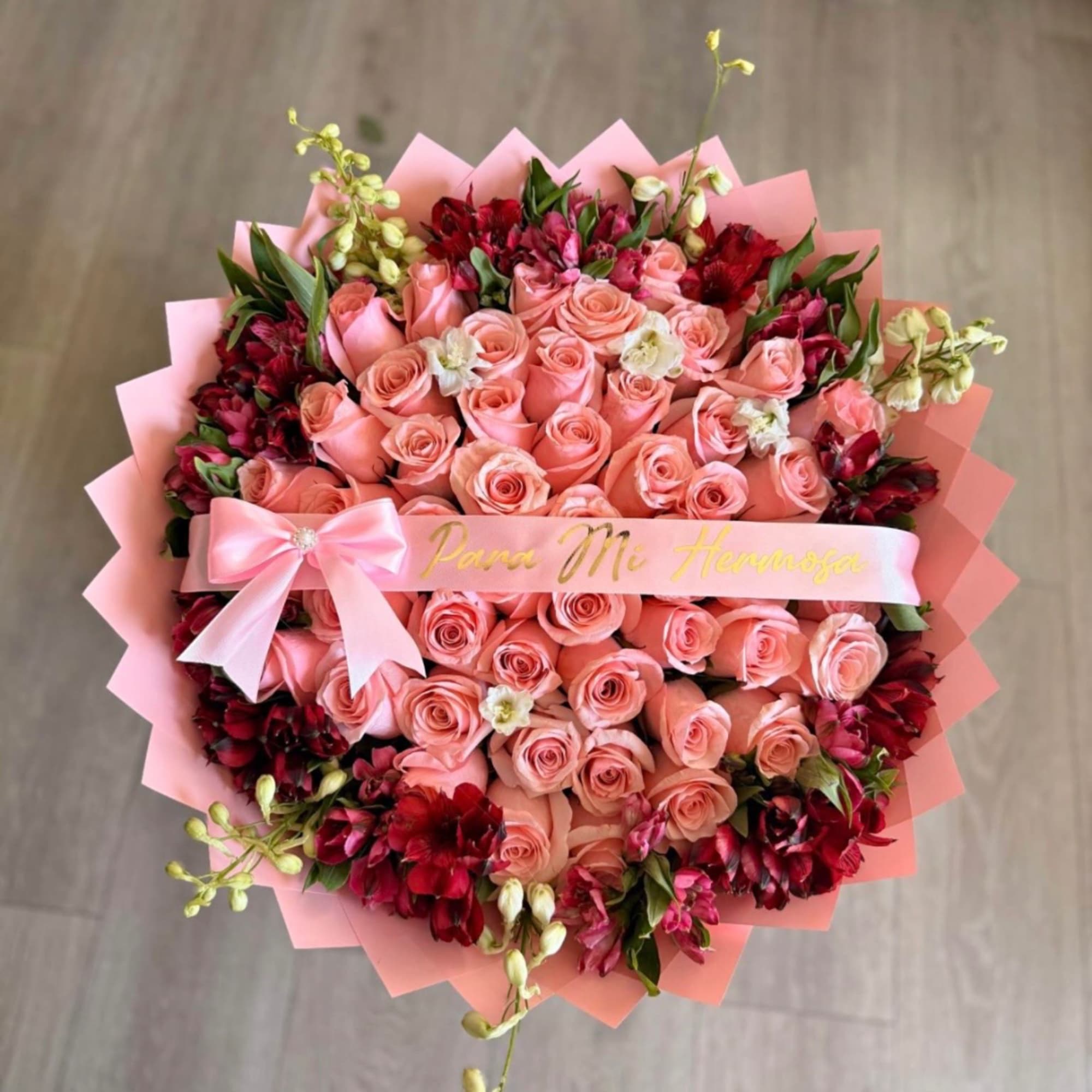Pink rose bouquet with red accent flowers and a satin ribbon