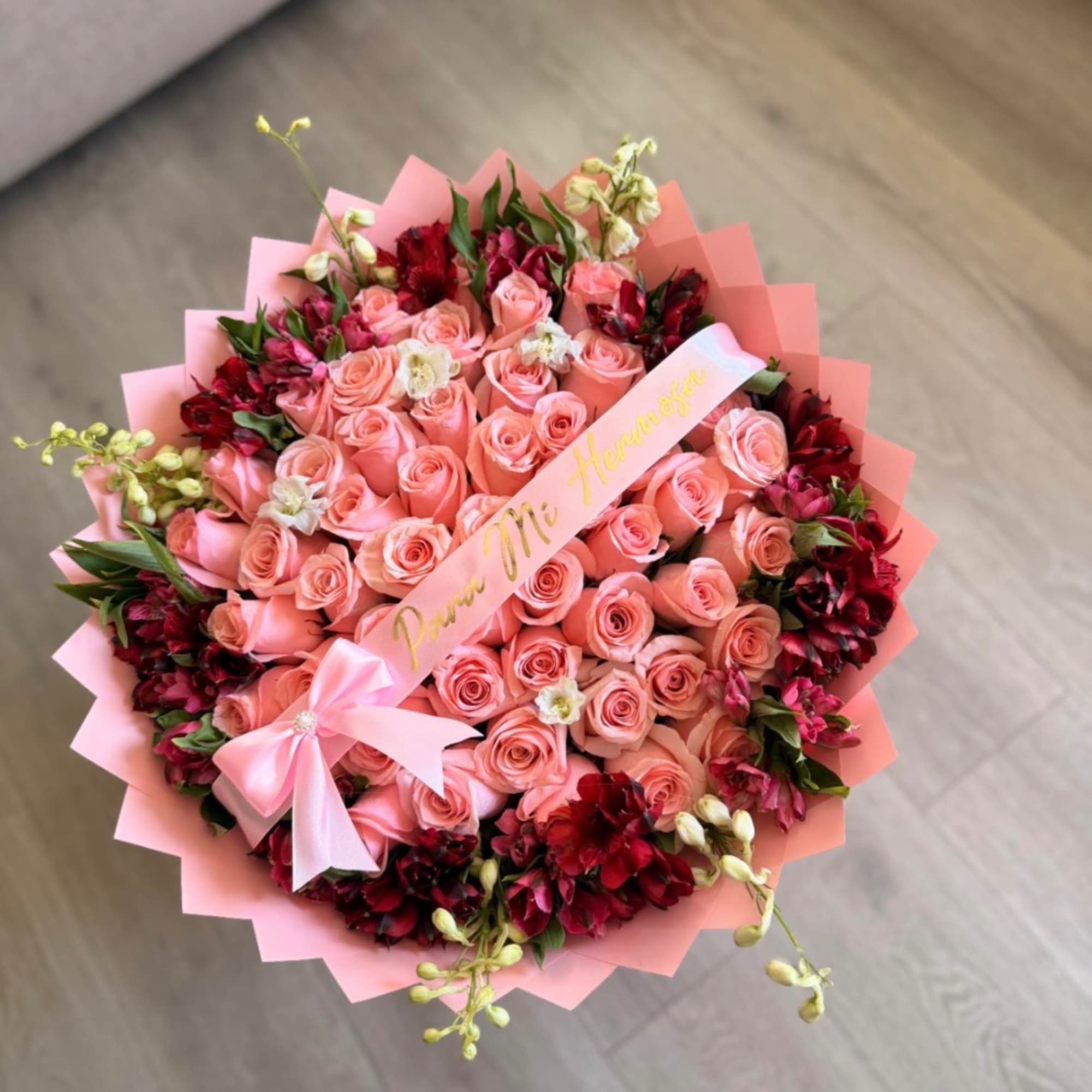 Pink rose bouquet with red accent flowers and a ribbon
