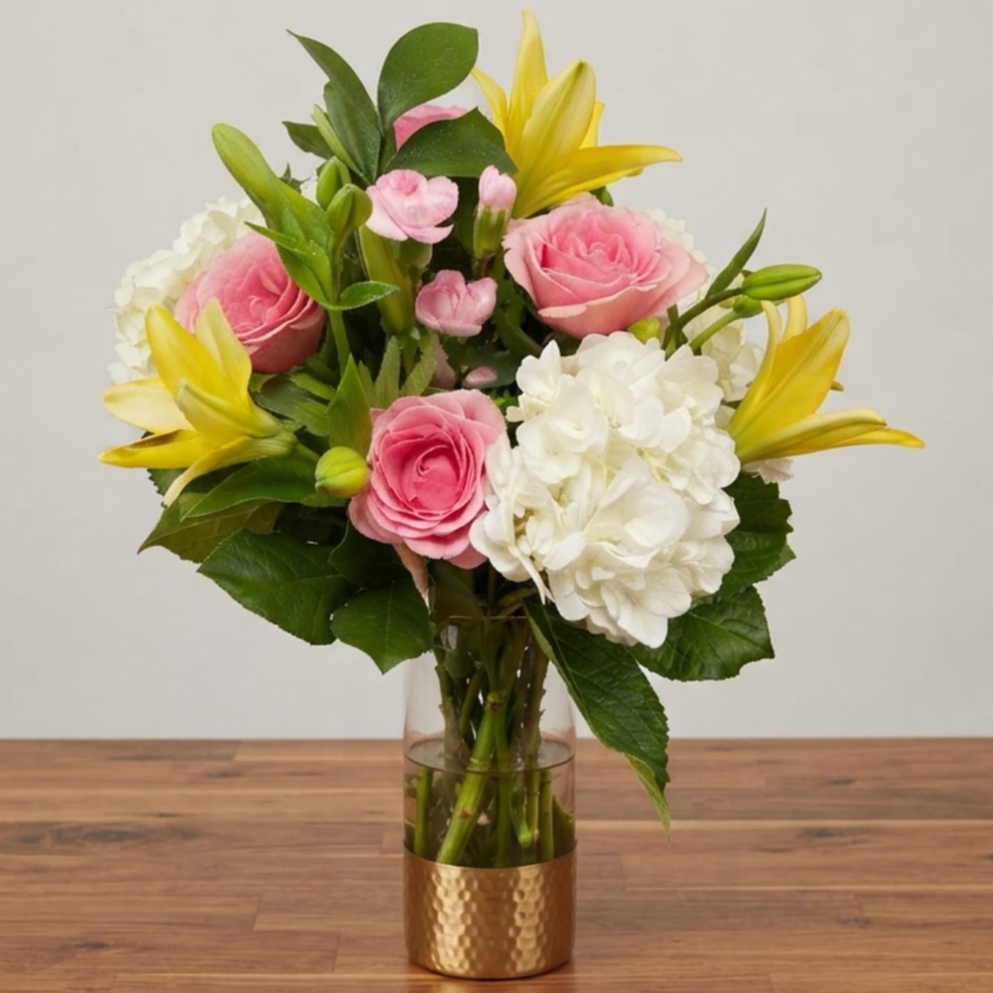 Pink roses and white hydrangeas with yellow lilies in a glass vase