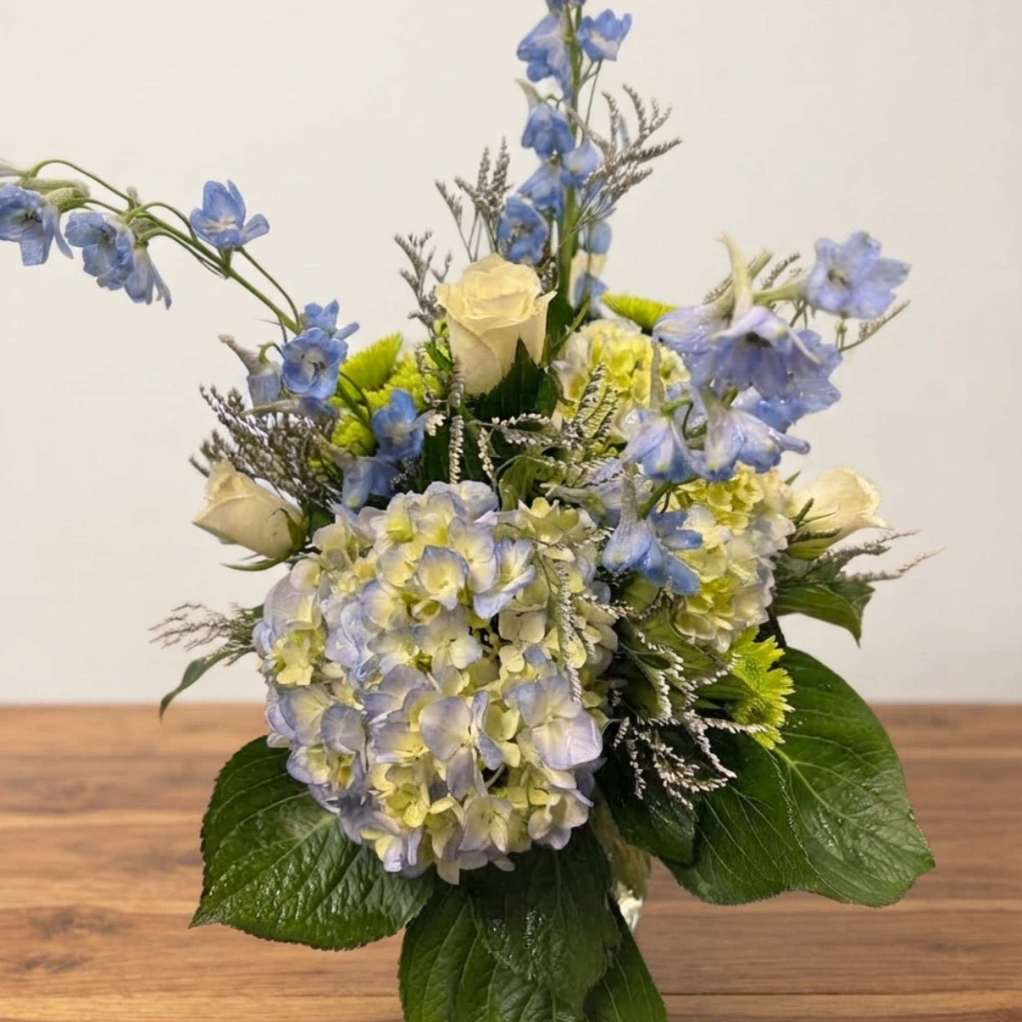 Blue and pale yellow flower arrangement with hydrangeas and roses