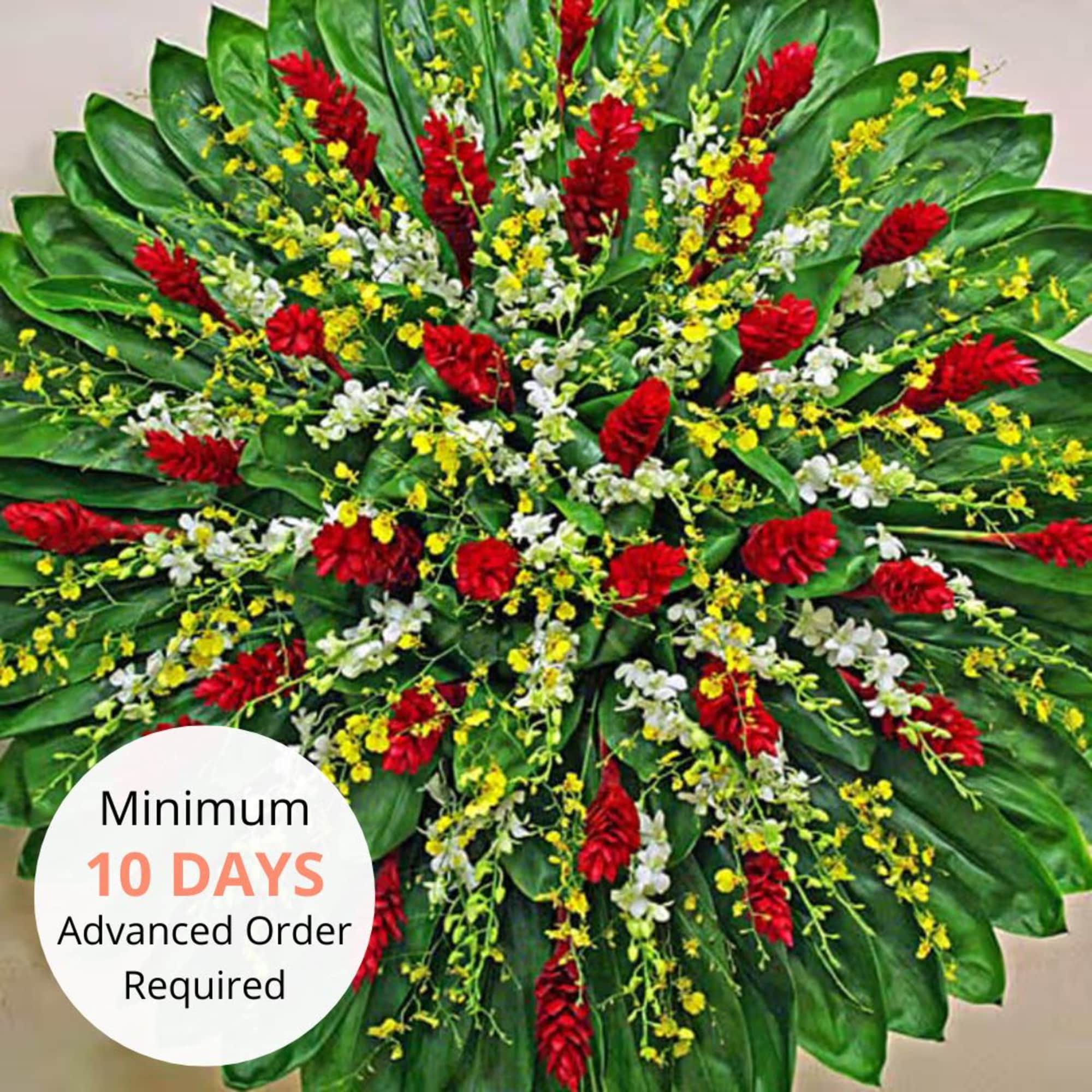 Large radial tropical arrangement with red flowers, yellow and white orchids and bold green leaves