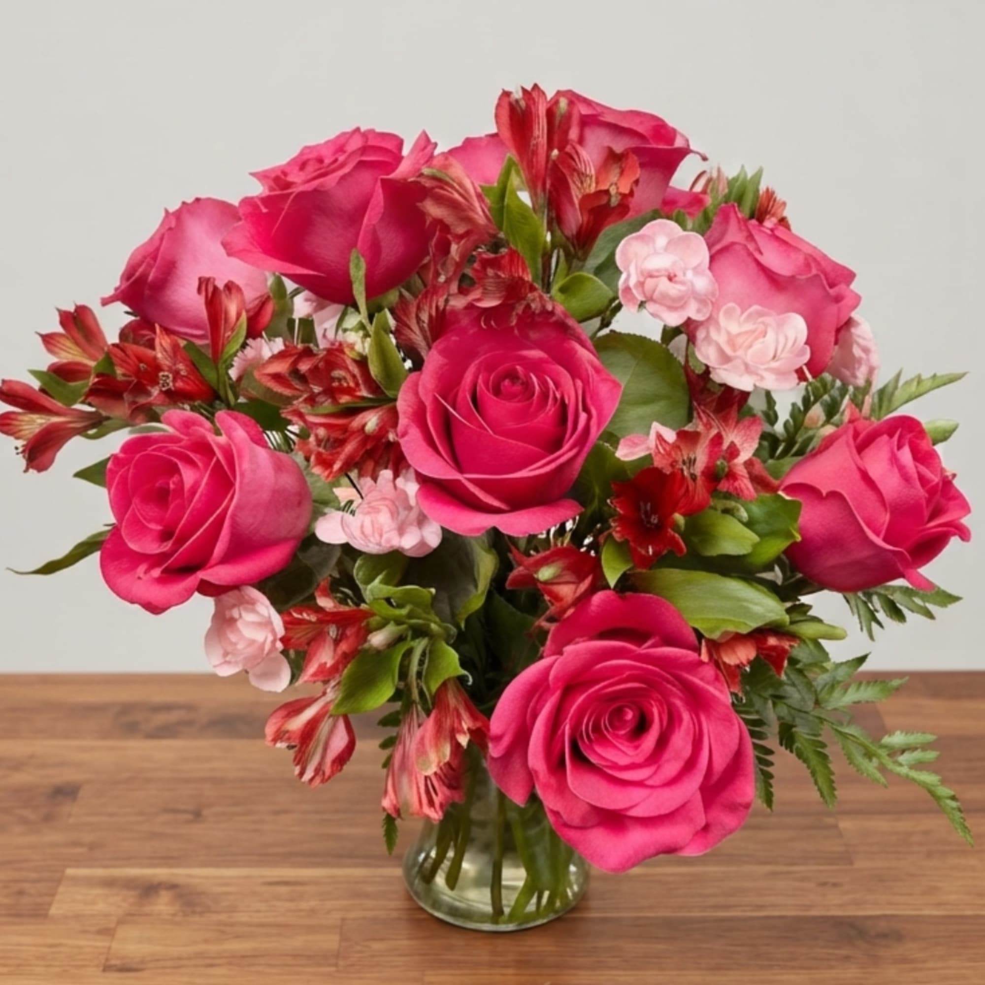 Pink roses and red alstroemeria in a clear glass vase
