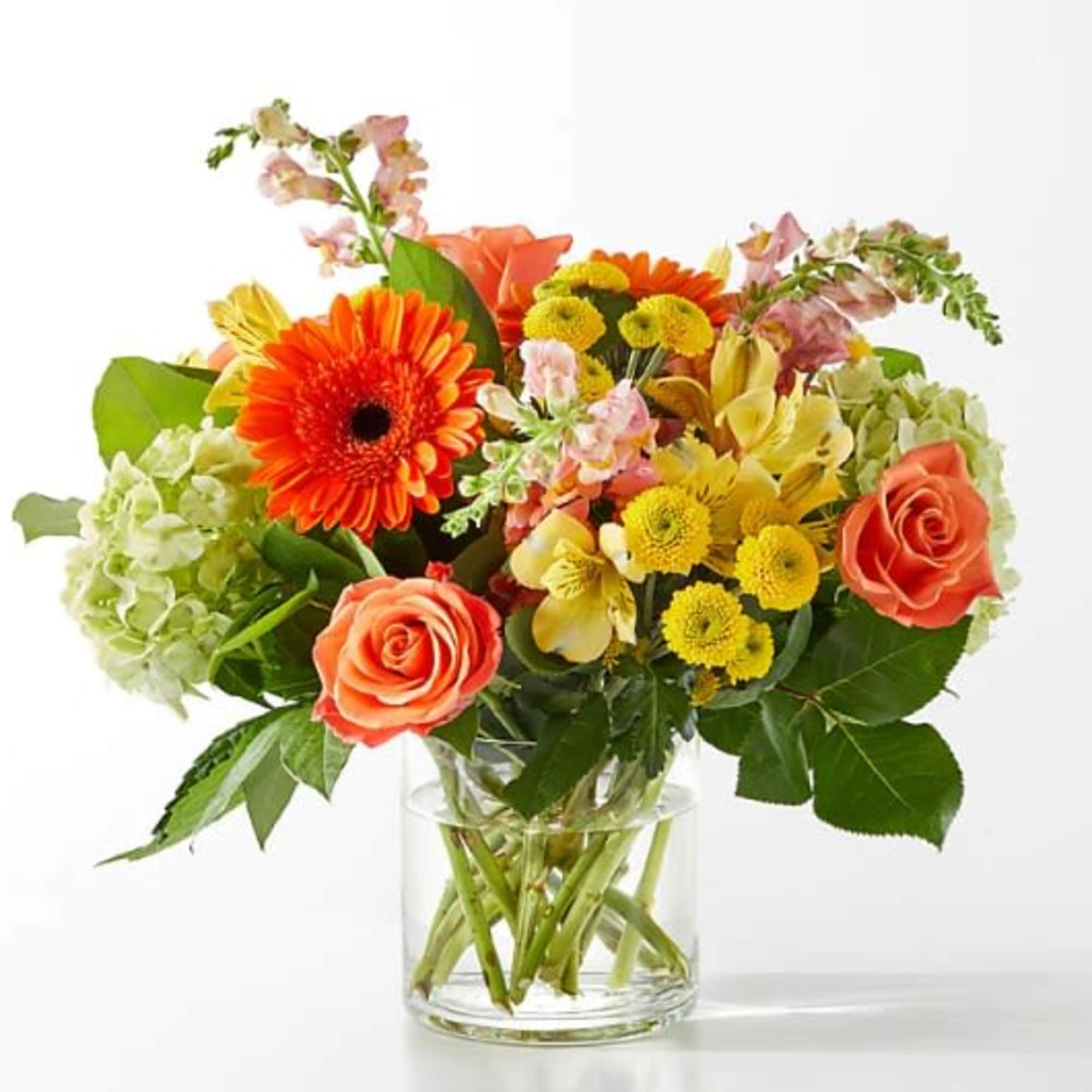 Mixed bouquet of orange and yellow flowers in a clear glass vase
