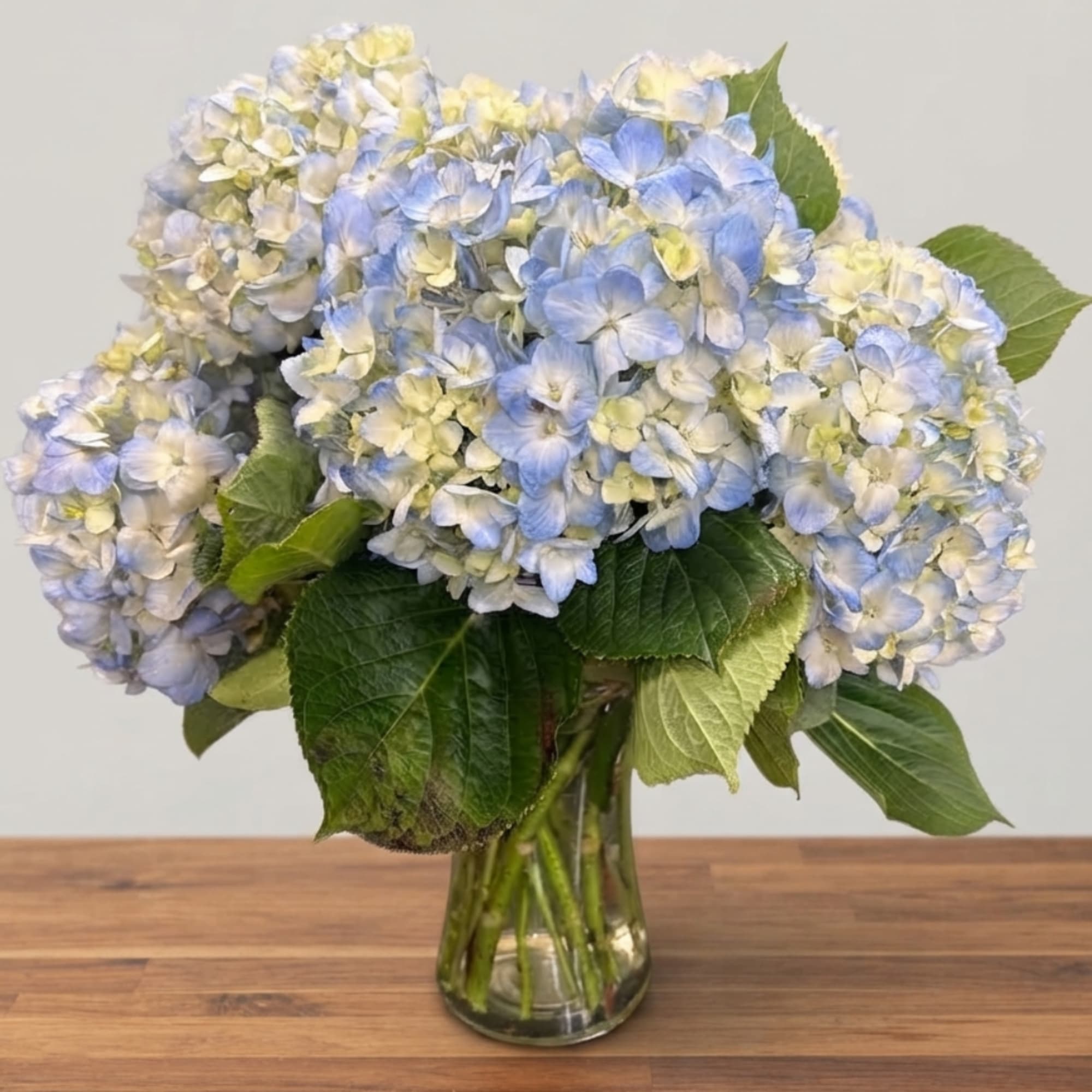 Blue and white hydrangea bouquet in a clear glass vase, photo 2 of 3