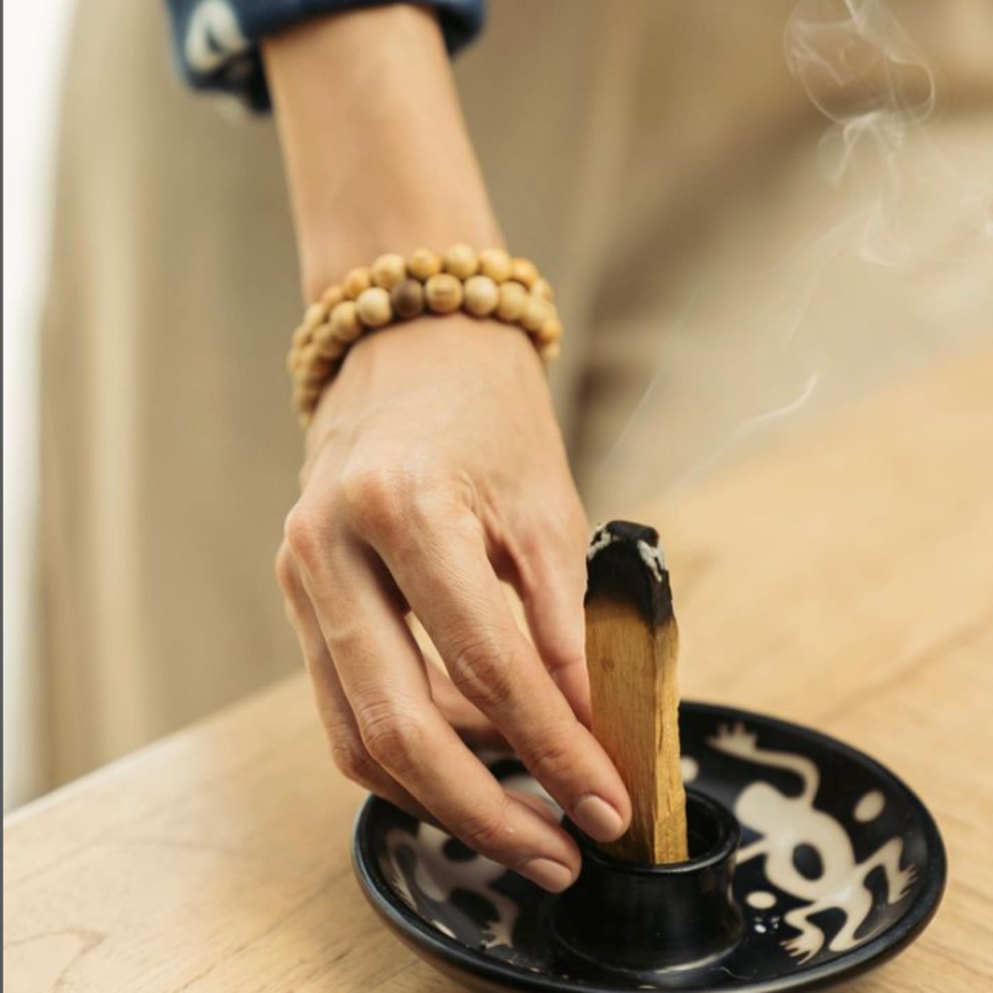 Hand lighting incense in a black ceramic holder