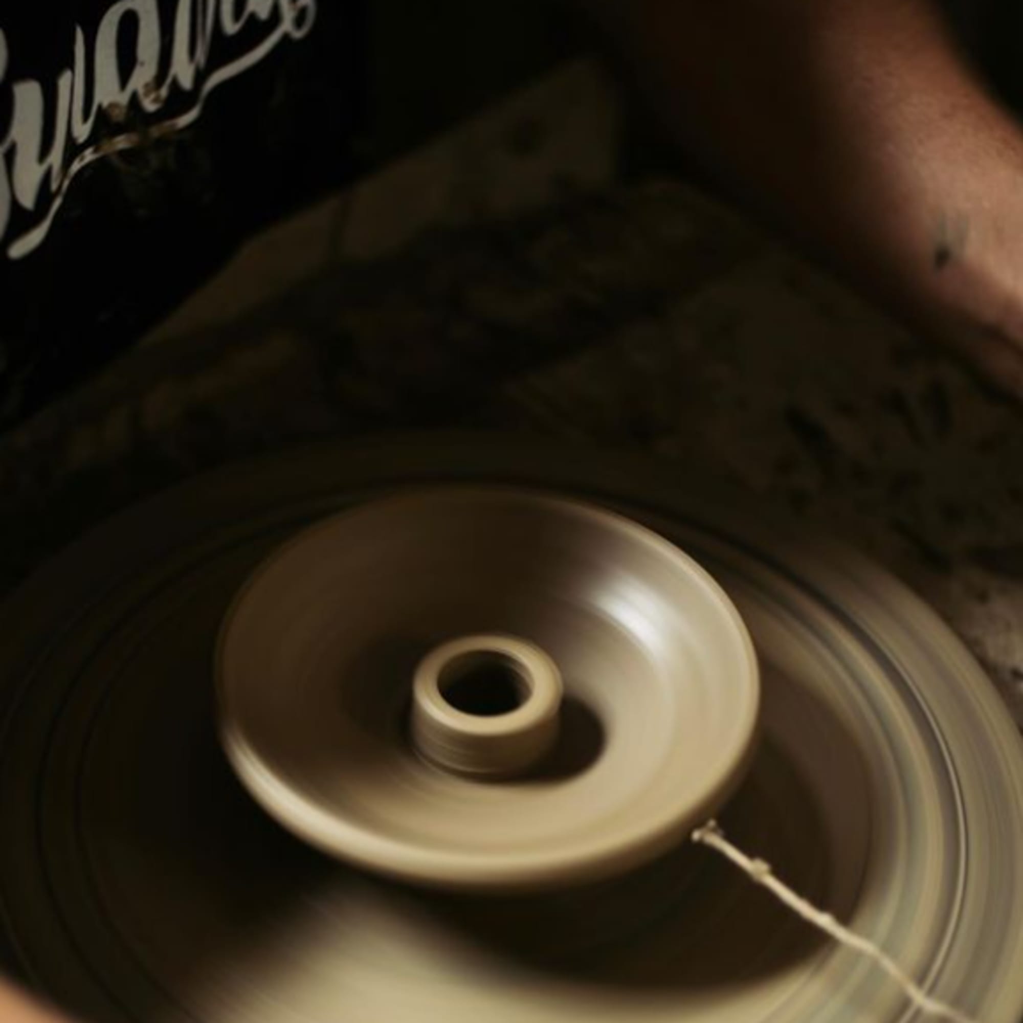 Person using a spinning pottery wheel with clay in progress