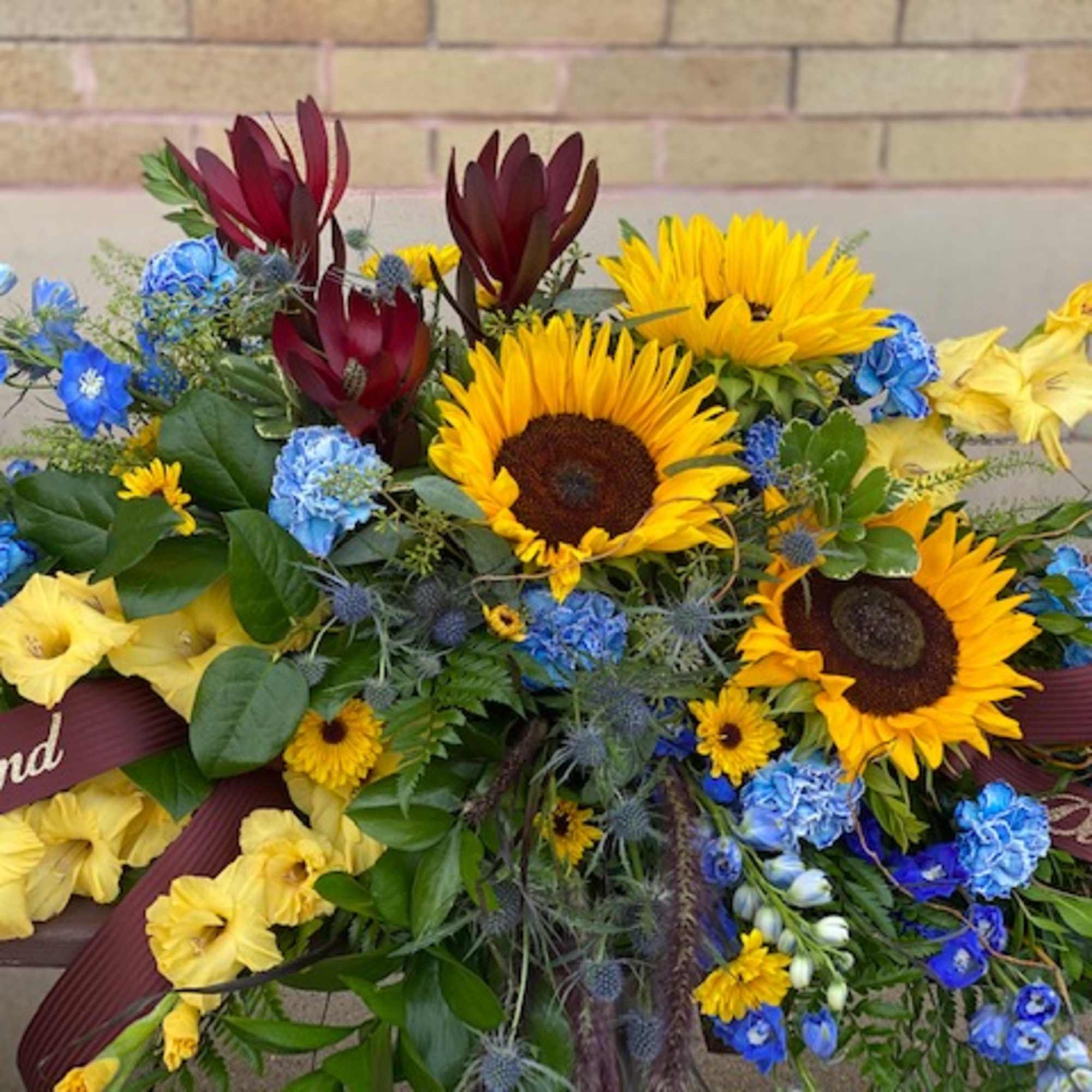 Bouquet with sunflowers, blue flowers, and yellow blooms tied with ribbons