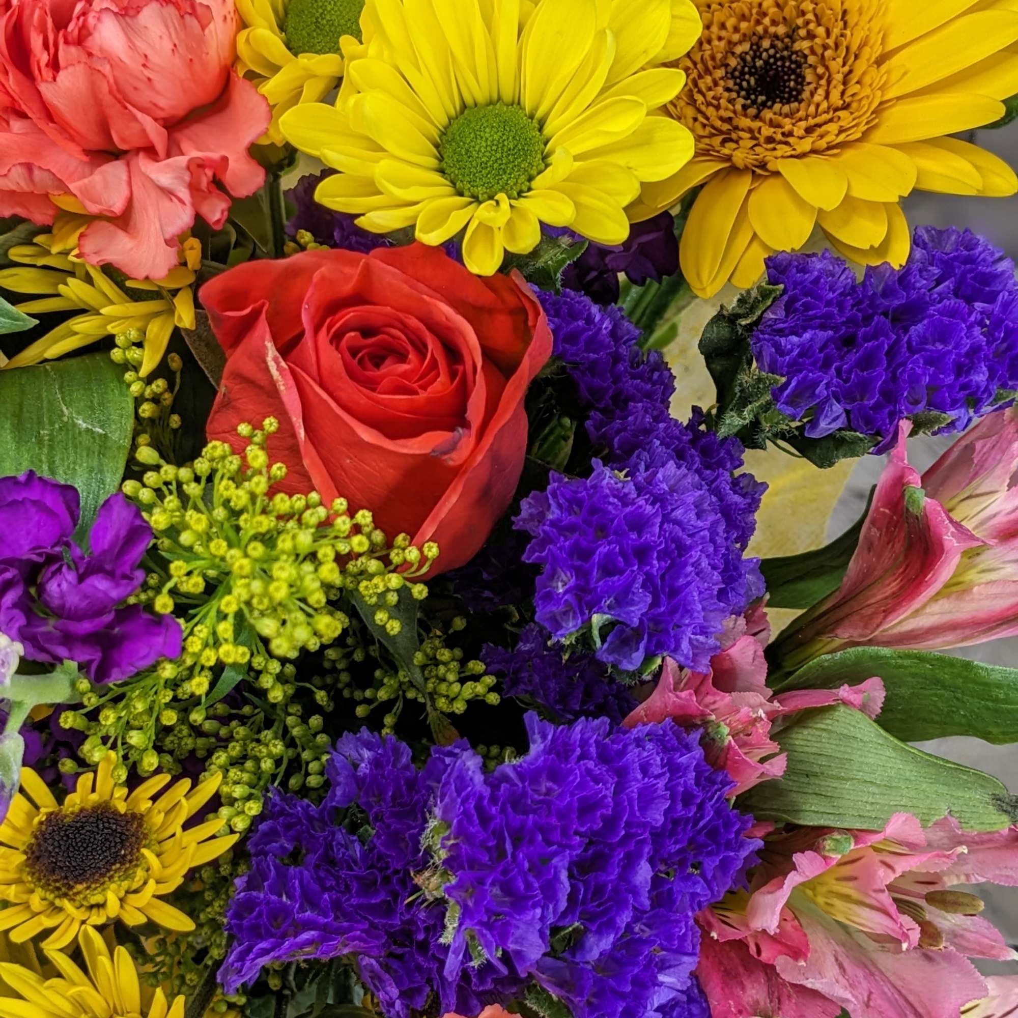 Colorful bouquet with yellow daisies, red rose, and purple filler flowers