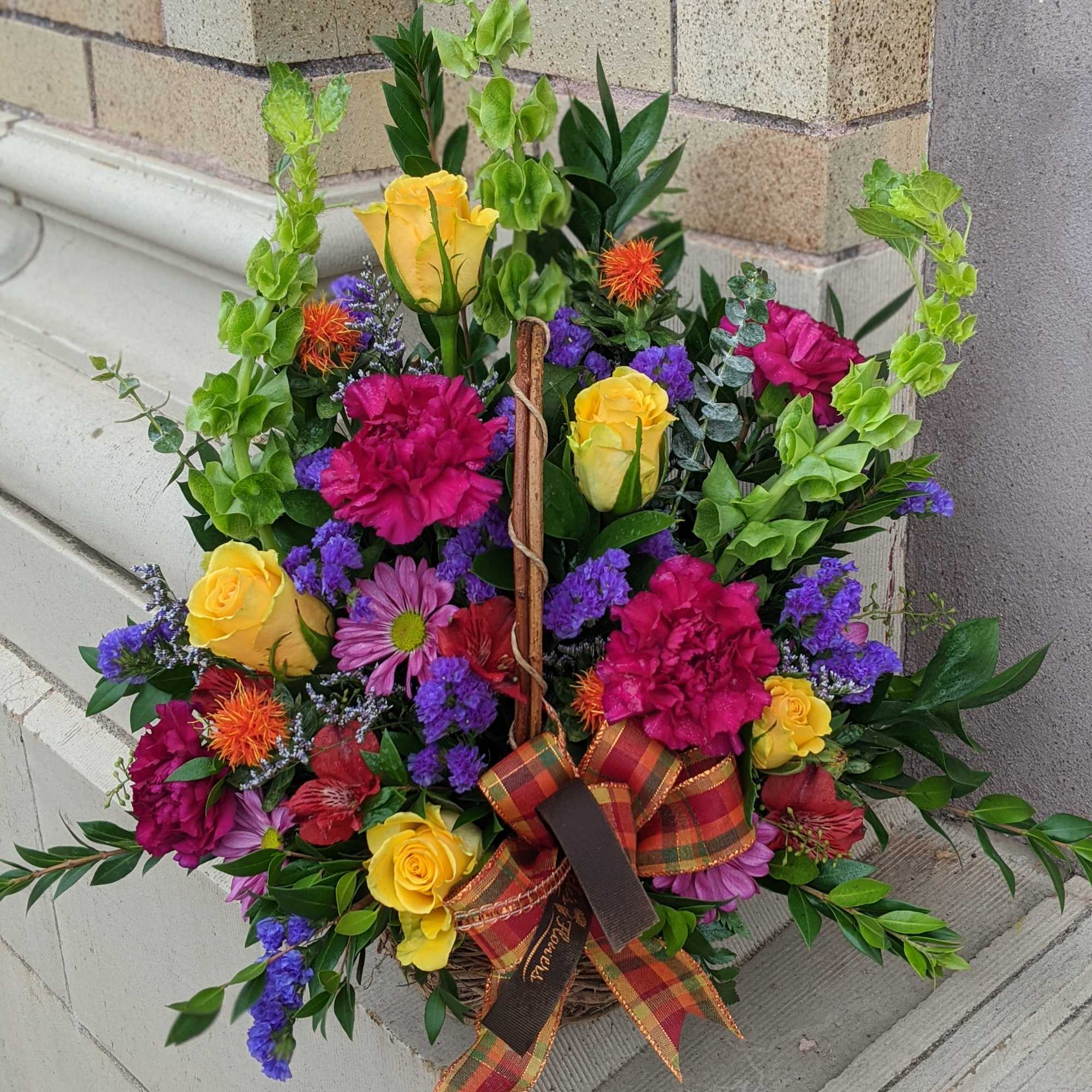 Colorful flower basket with yellow roses, pink carnations, and purple blooms