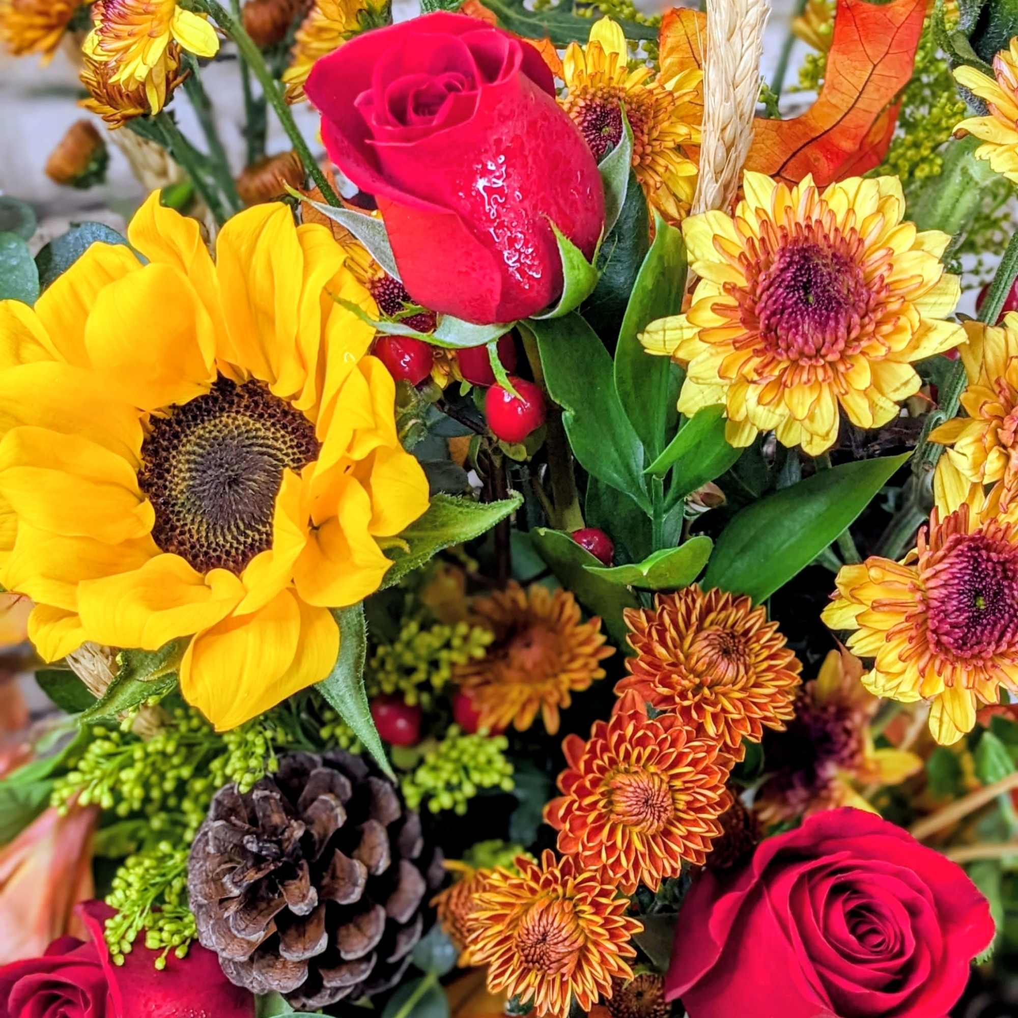 Bouquet with red roses, sunflowers, and autumn mums with a pinecone accent