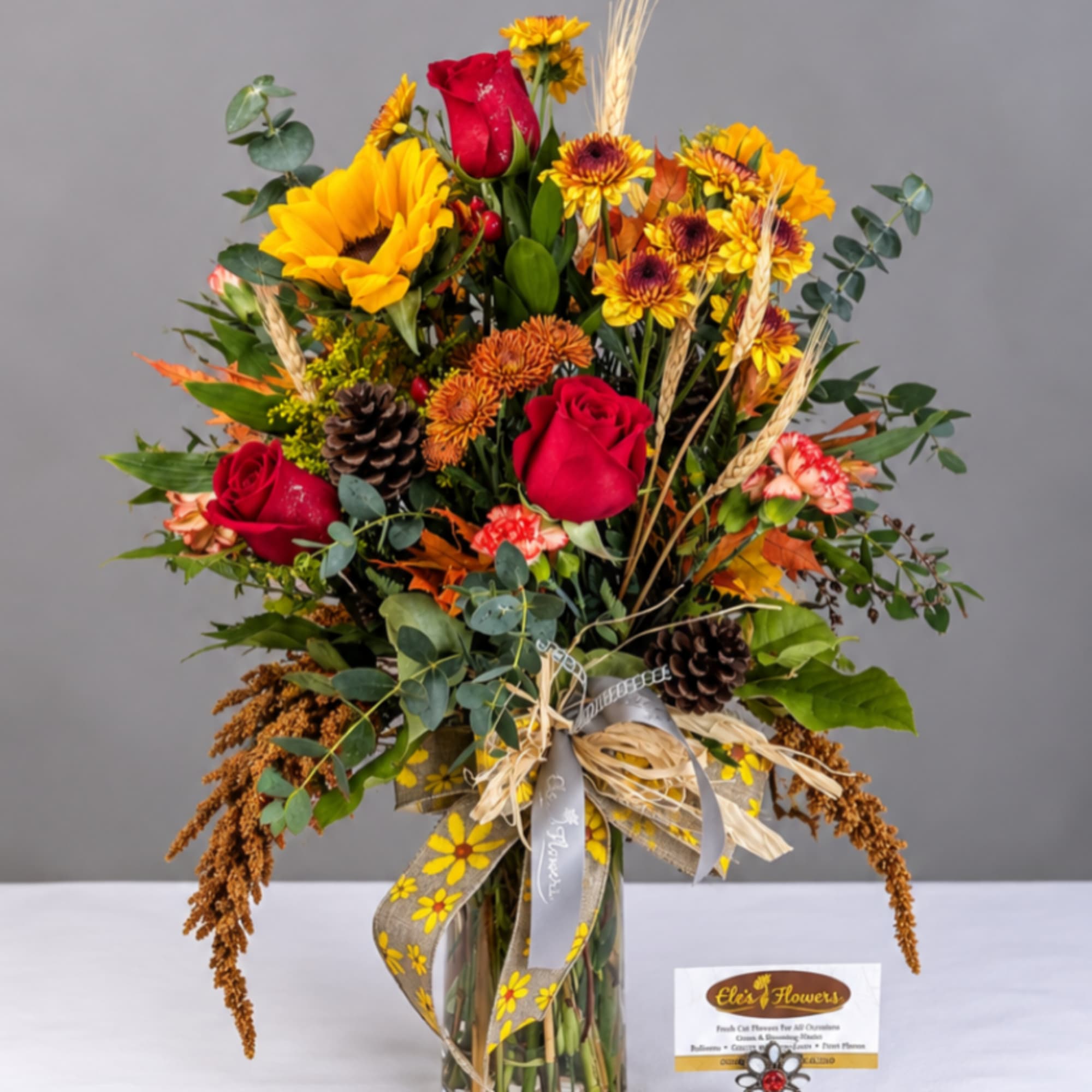 Mixed bouquet of red roses and sunflowers in a glass vase