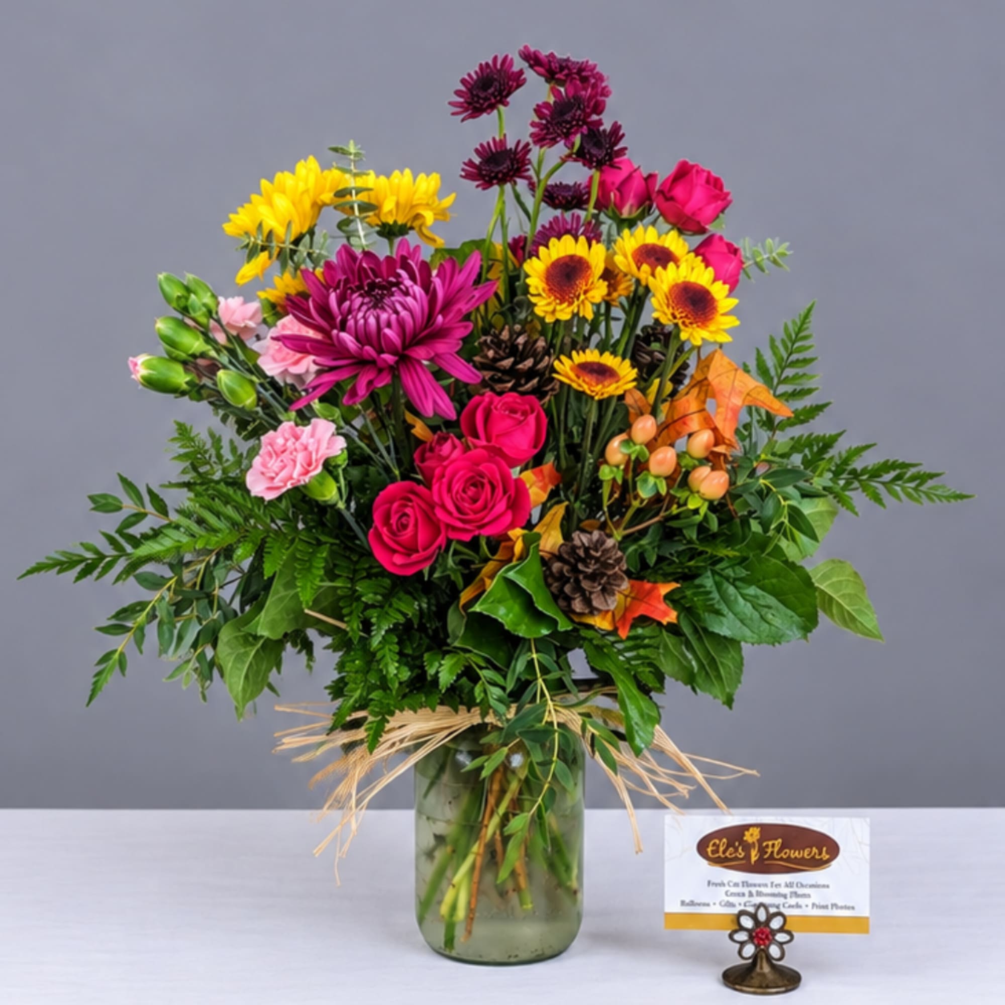 Mixed bouquet of pink, yellow, and purple flowers in a glass vase