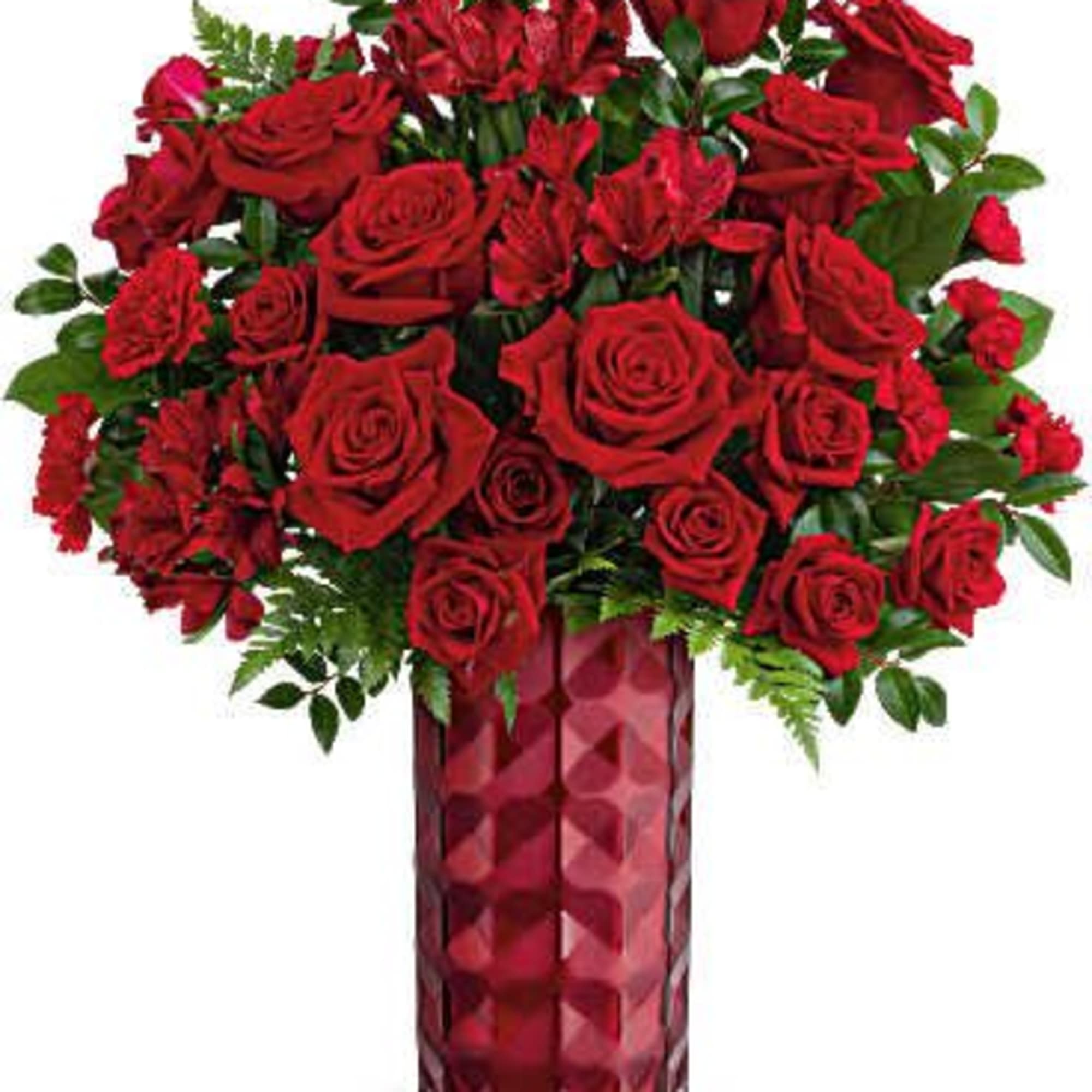 Red roses arranged in a tall glass vase with greenery