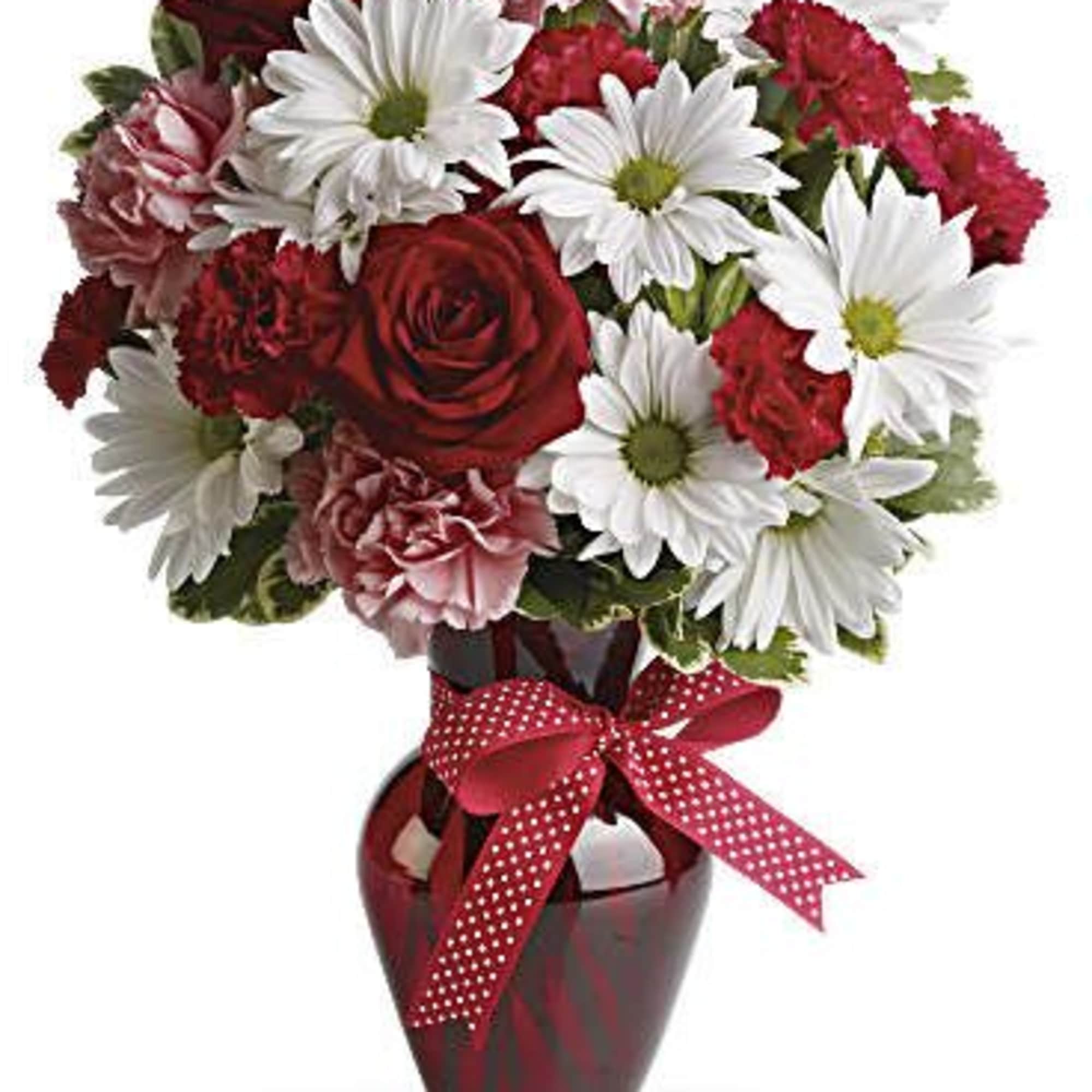 Bouquet of red roses, white daisies, and pink carnations in a red vase with ribbon