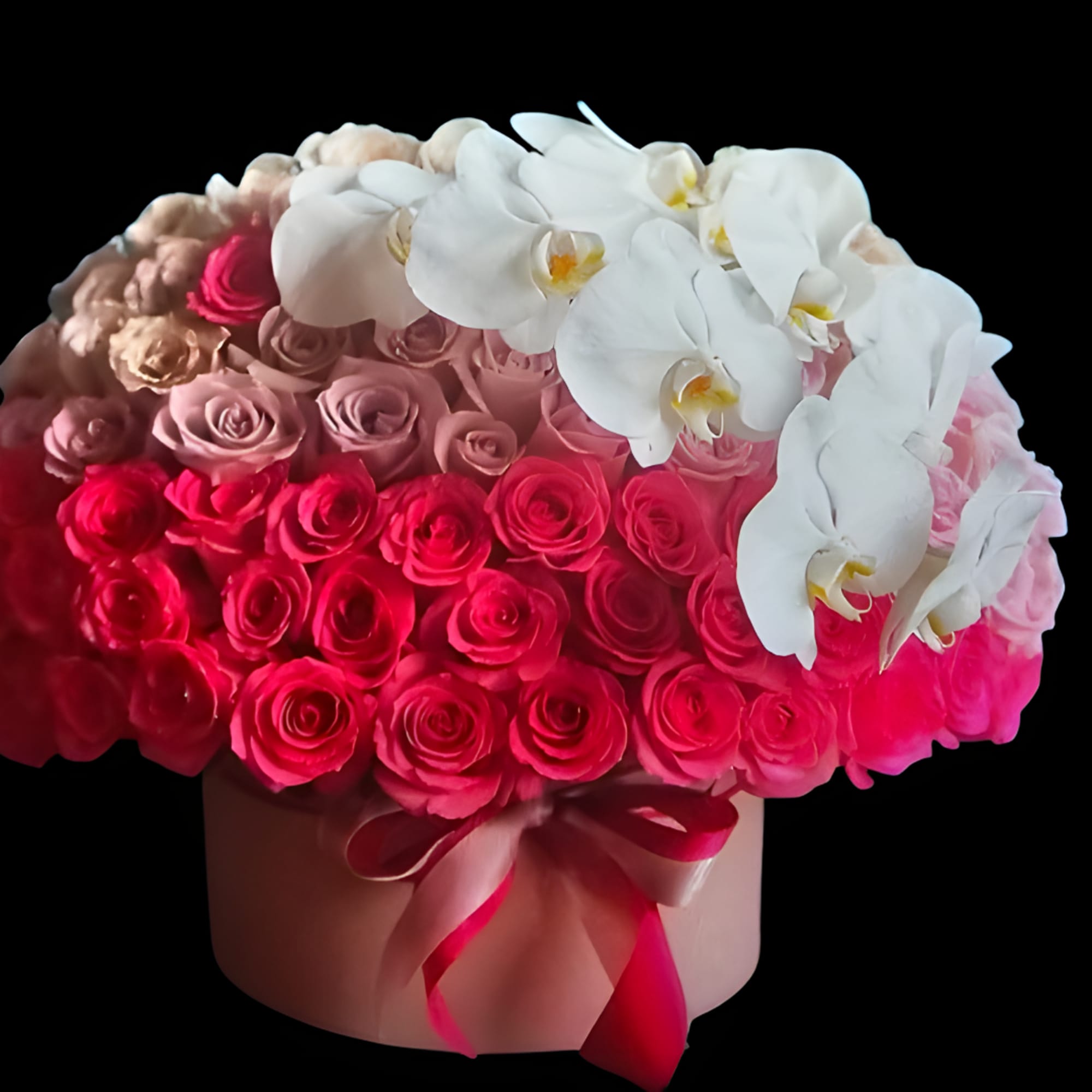 Pink roses and white orchids arranged in a round hat box
