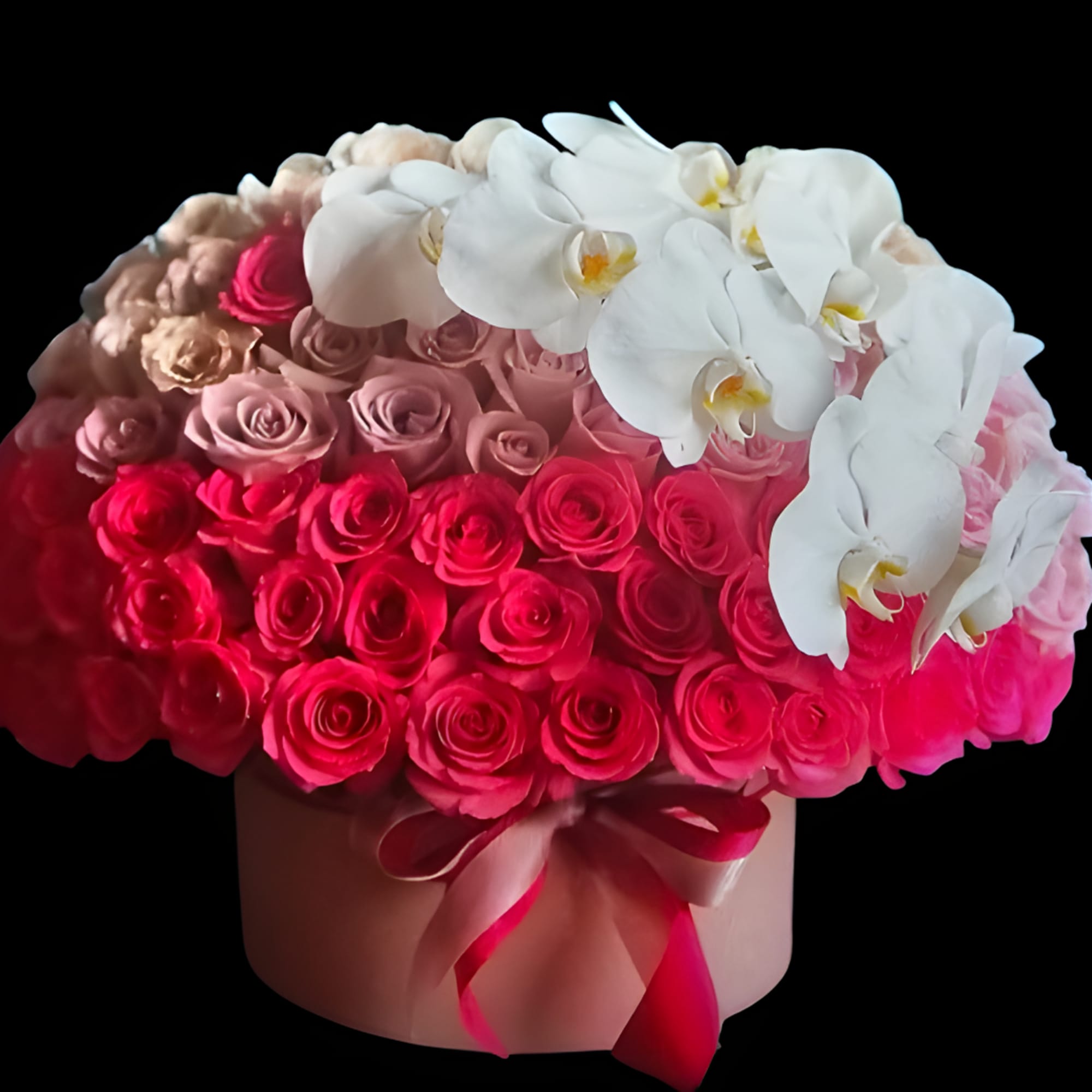 Round box arrangement of pink roses topped with white orchids